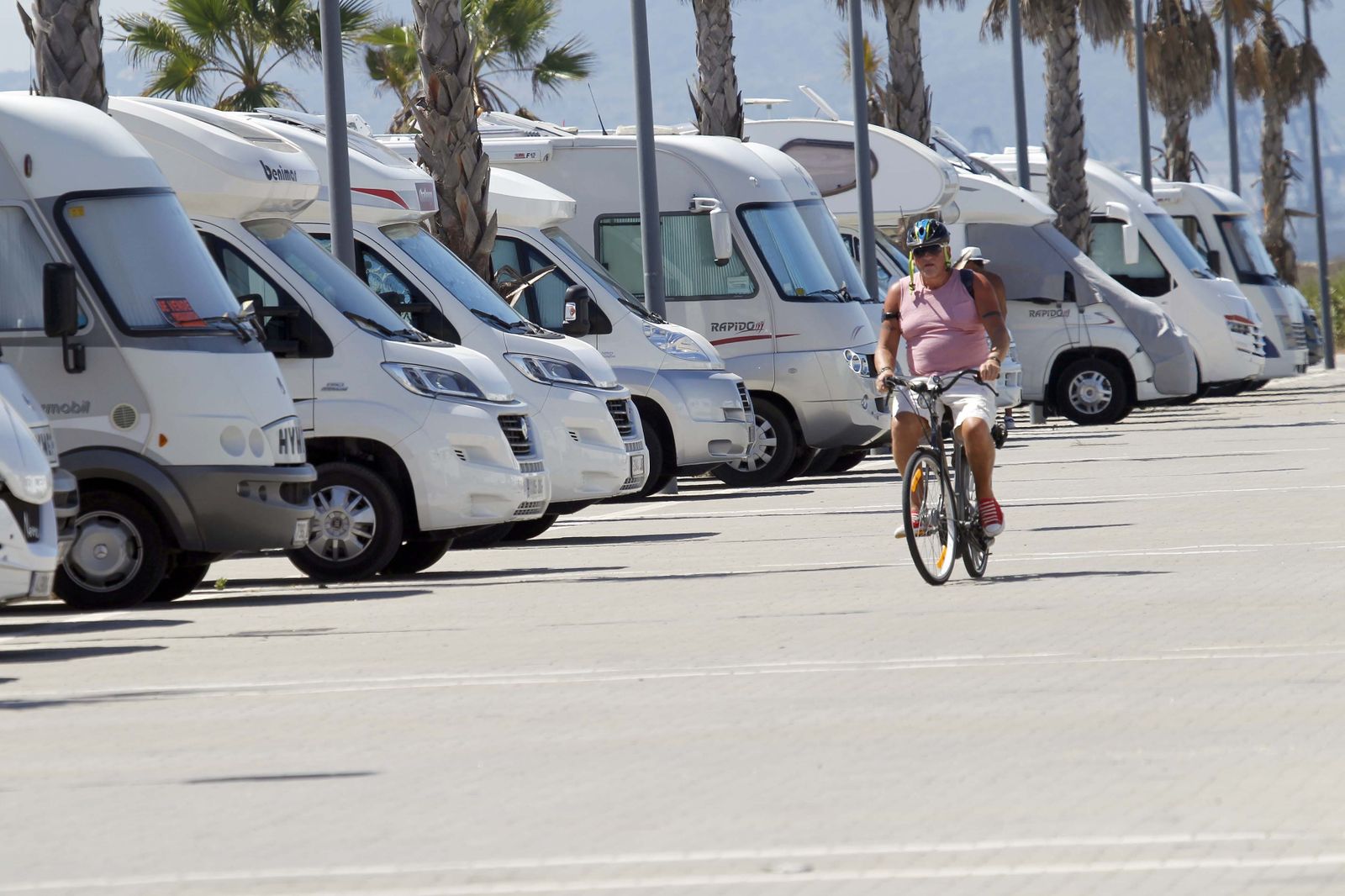 Una persona circula en bicicleta junto a un aparcamiento de autocaravanas.