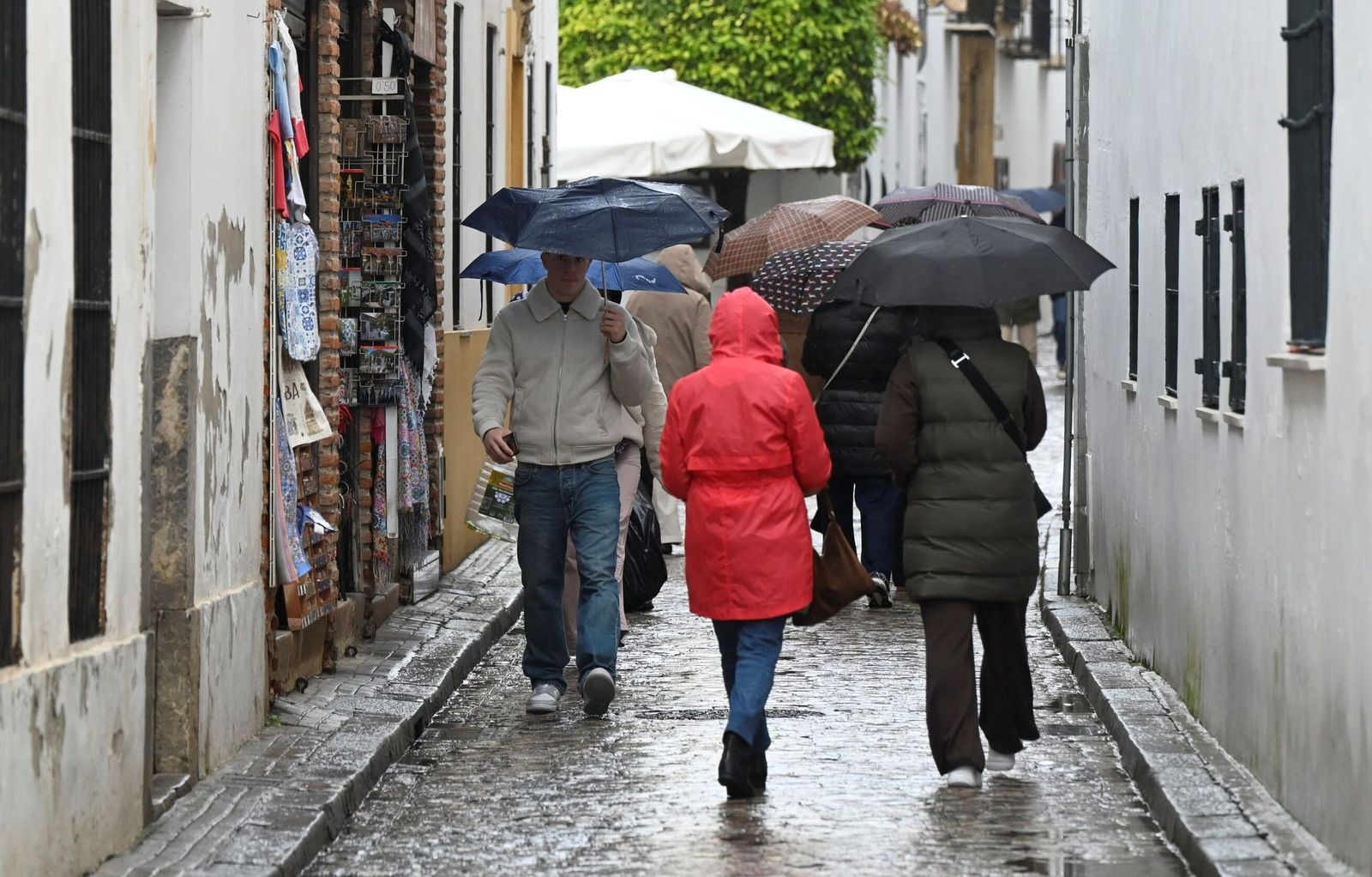 Varias personas caminan por la Judería de Córdoba bajo la lluvia.