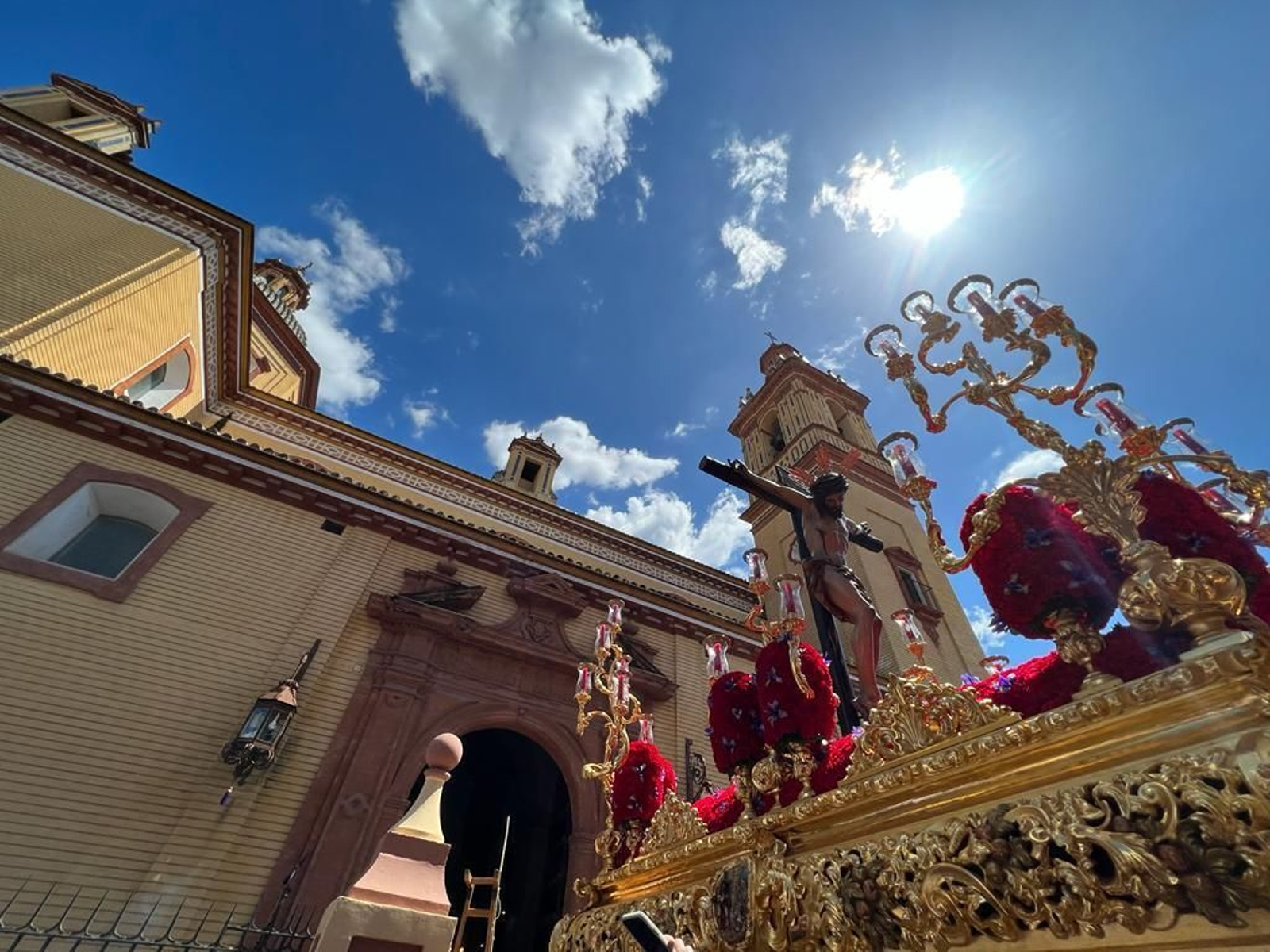 Un cielo azul recibe al Cristo de la Salud tras salir de la parroquia de San Bernardo.