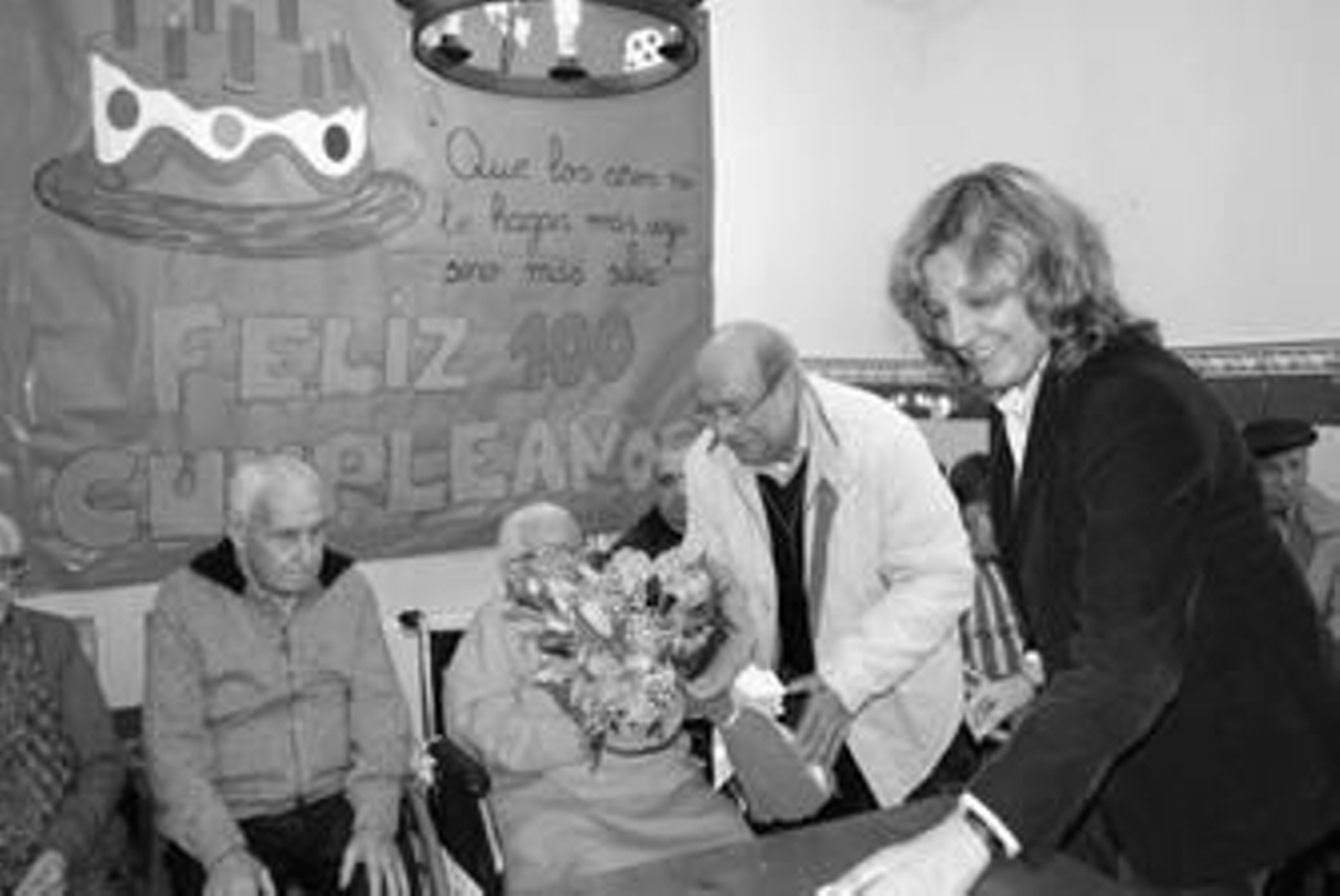 José Vázquez entrega un ramo de flores a la anciana en presencia de la edil Rosa Macías.