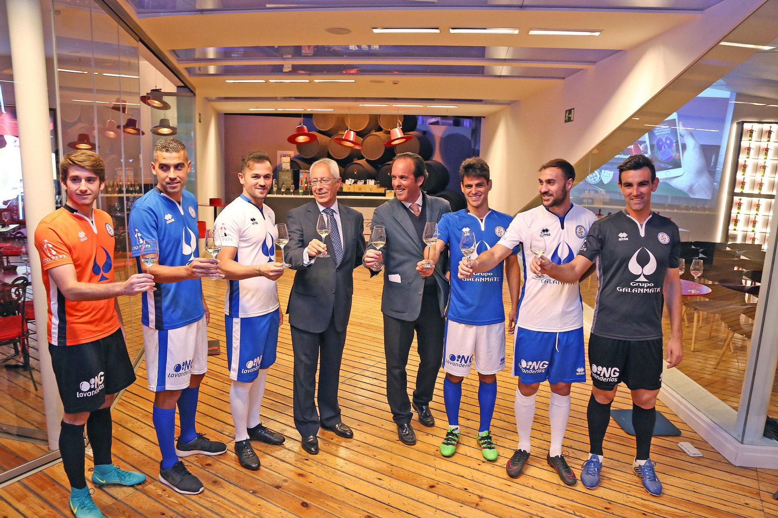 José Argudo y Rafael Coca posan con una copa de Tío Pepe junto a los futbolistas que acudieron al acto.