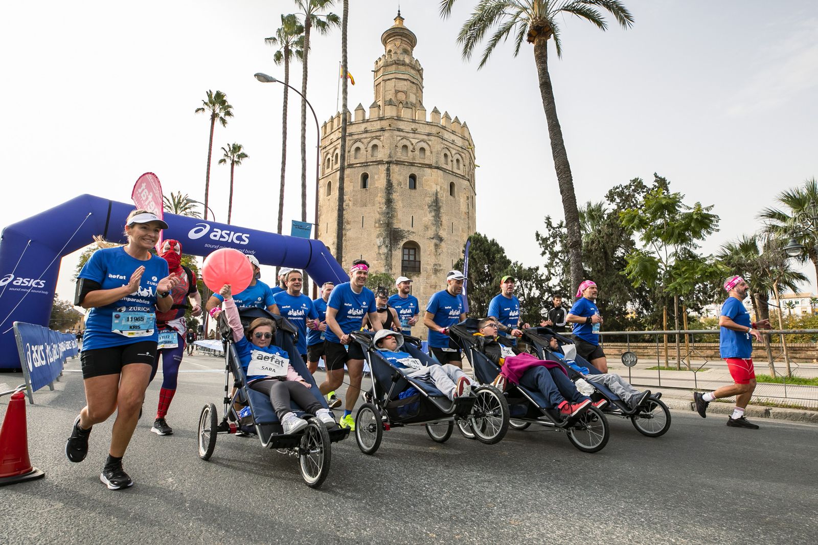 Los jóvenes con ataxia telangiectasia pasando por la Torre del Oro en la Zurich Maratón Sevilla.