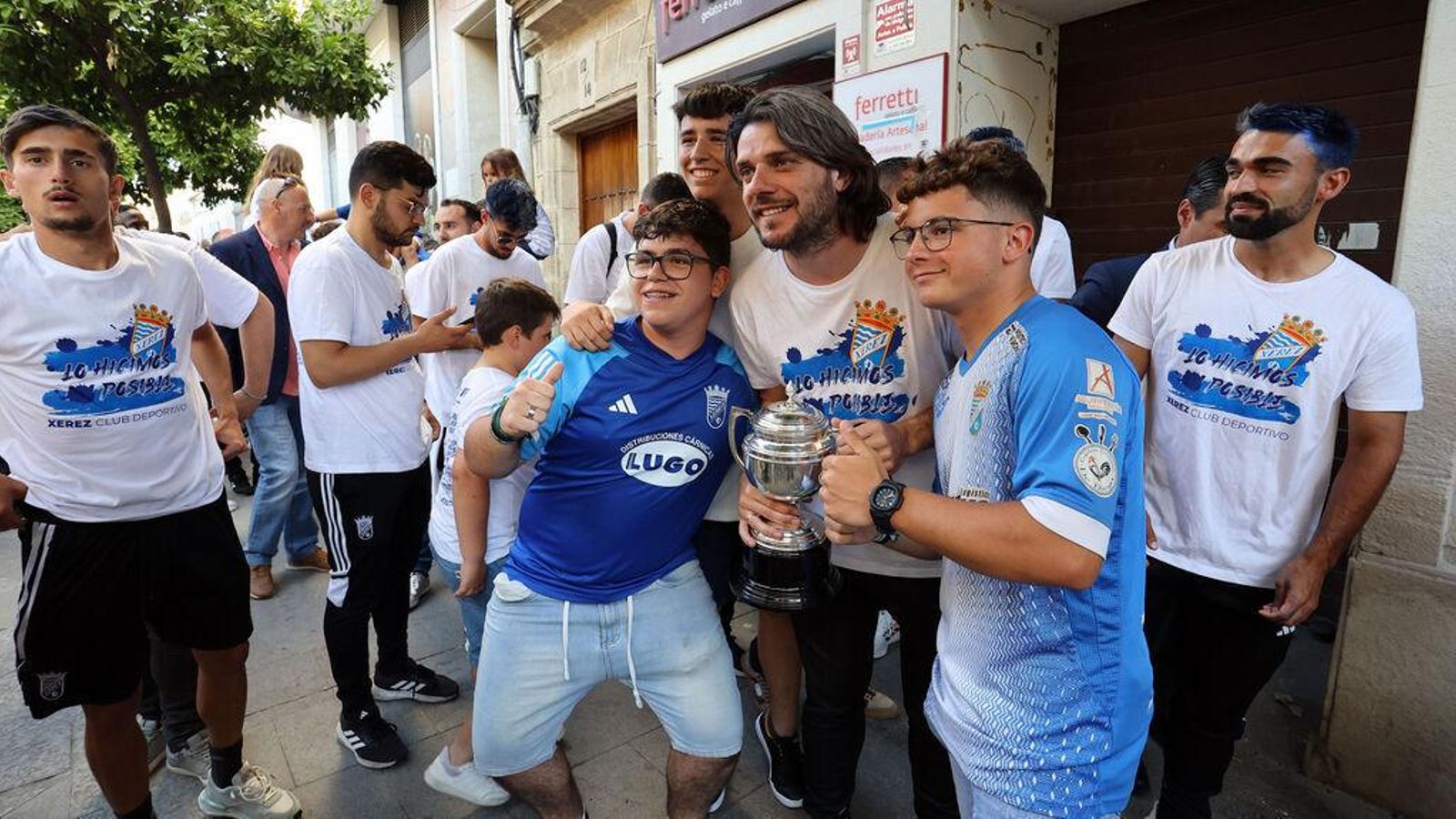 Migue García posa junto a unos niños con la copa de campeones.