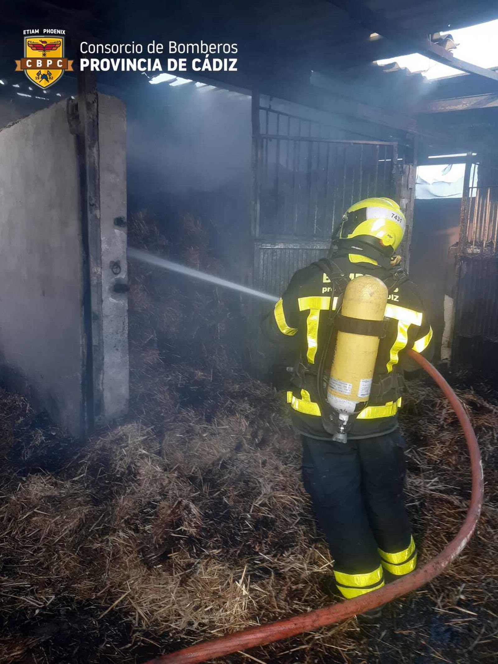 Un bombero sofocando el fuego dentro del establo.