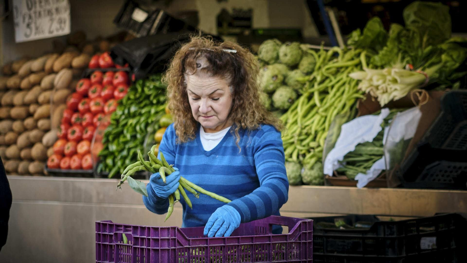 Una detallista del Mercado Central organizando la mercancía con guantes