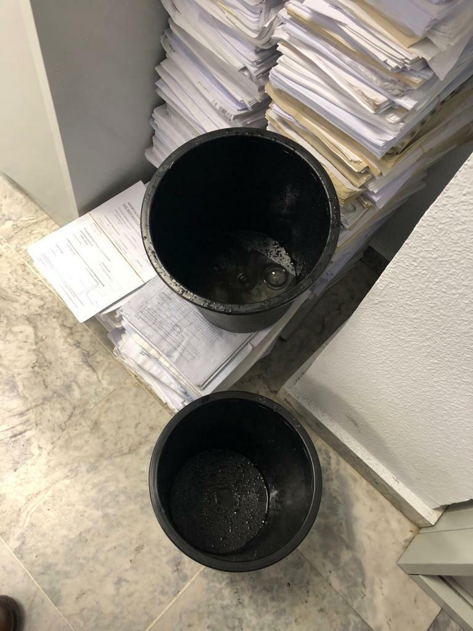 Los cubos colocados para recoger el agua que se cala junto a los expedientes.