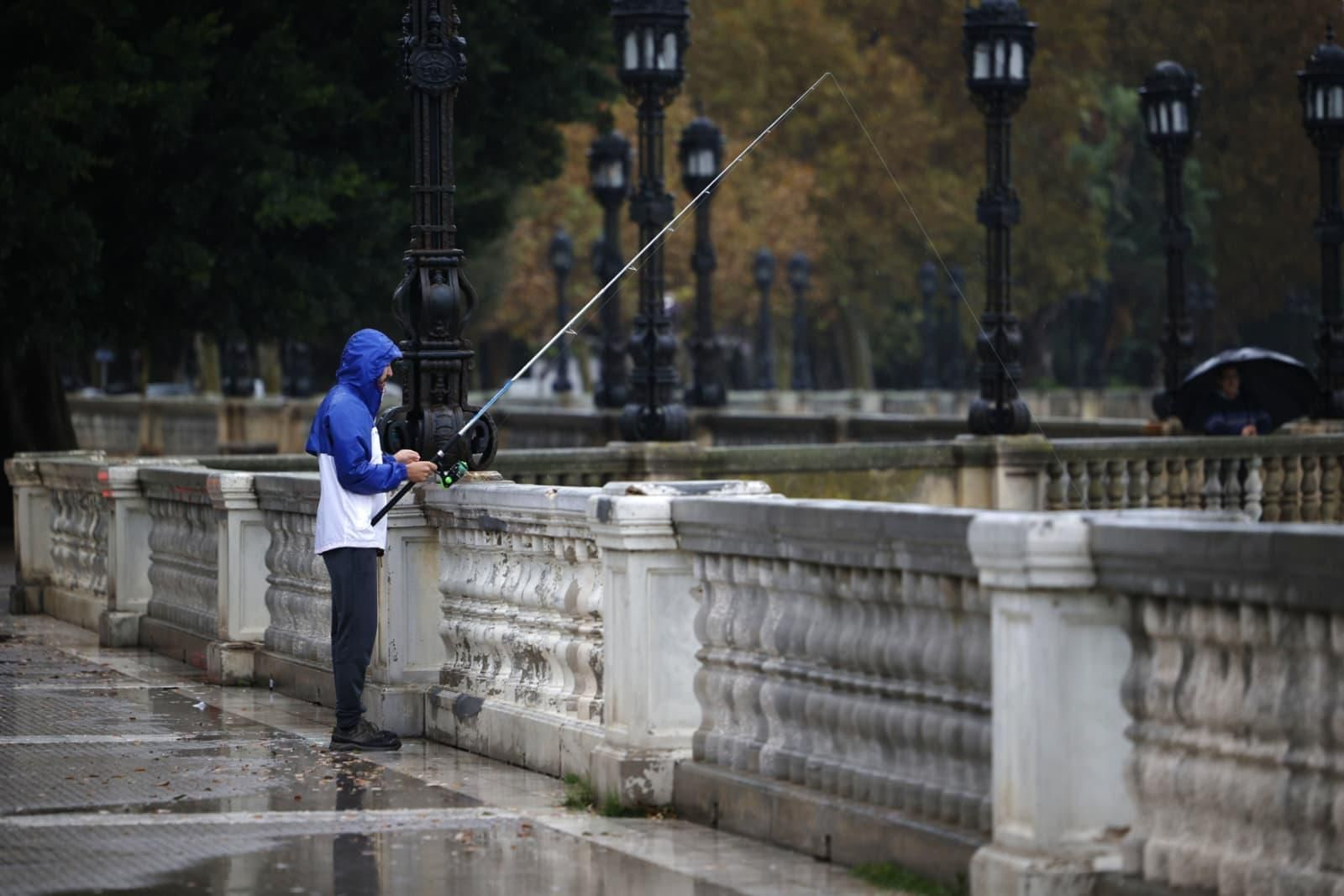 Un hombre intenta pescar desde la Alameda de Cádiz pese a la lluvia.