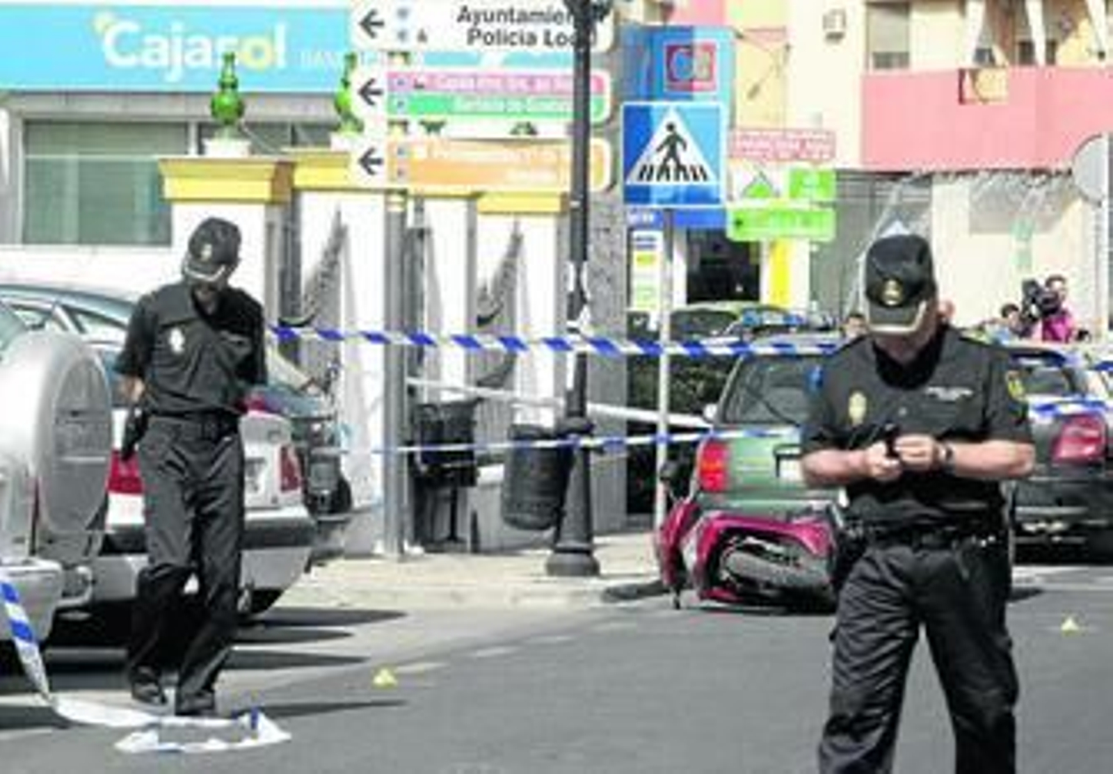 Dos policías examinan la zona del tiroteo junto a la sucursal asaltada por el Francés el pasado viernes.
