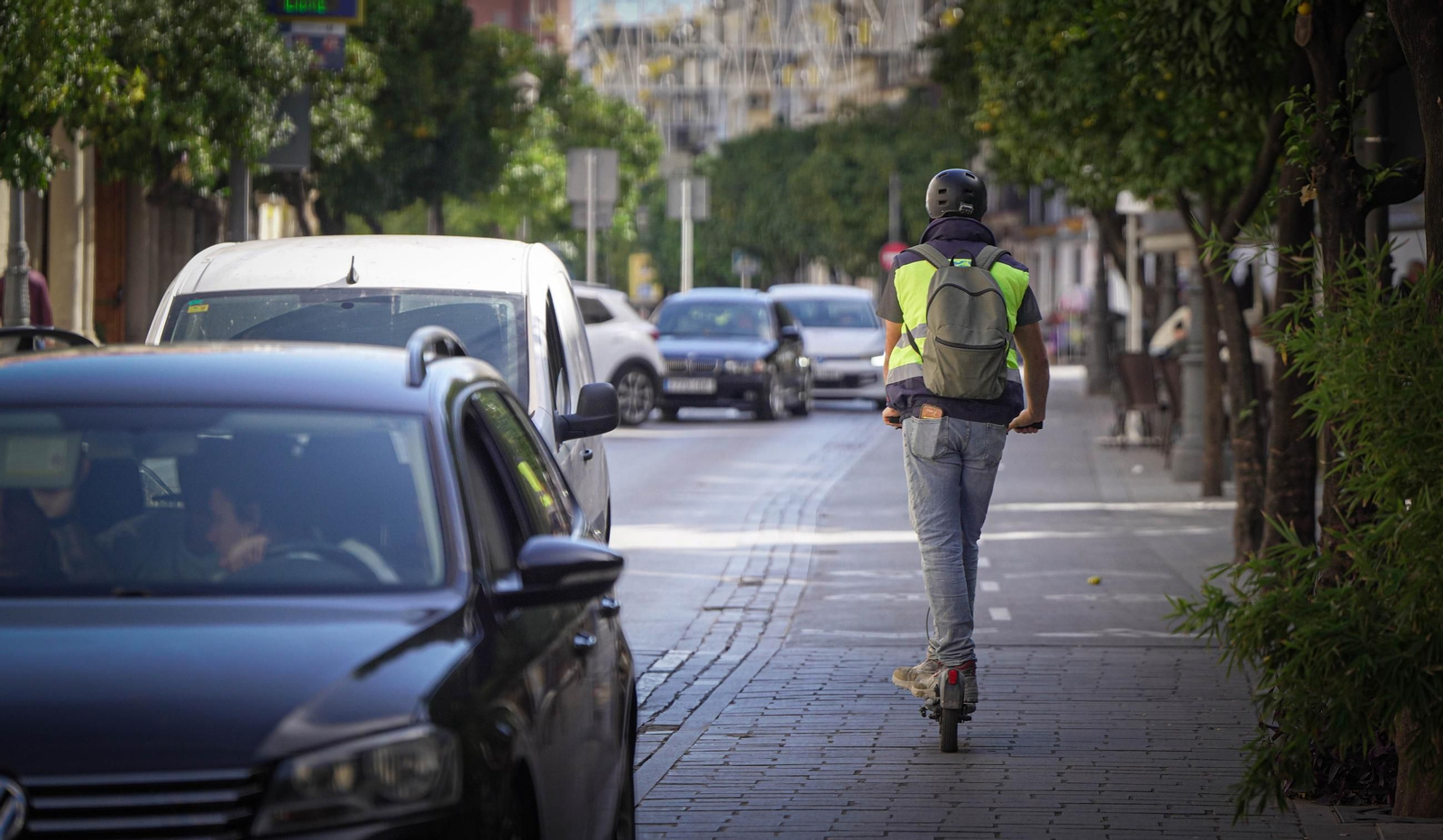 Una persona, conduciendo un patinete por una calle de la ciudad.