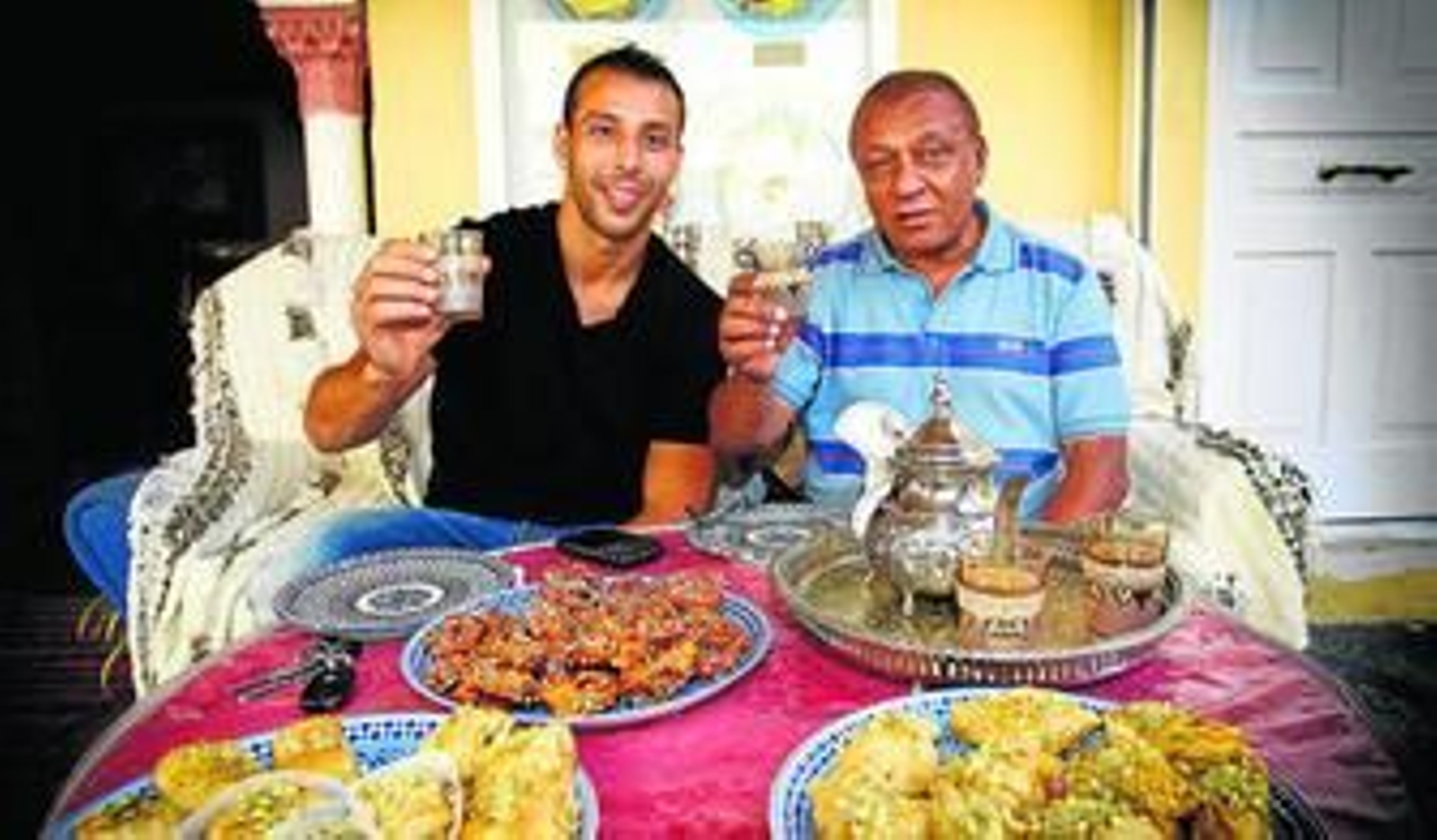 El Hamdaoui y Ben Barek brindan con un vaso de té moruno en una mesa rodeada de dulces típicos. El Hamdaoui y Ben Barek brindan con un vaso de té moruno en una mesa rodeada de dulces típicos.