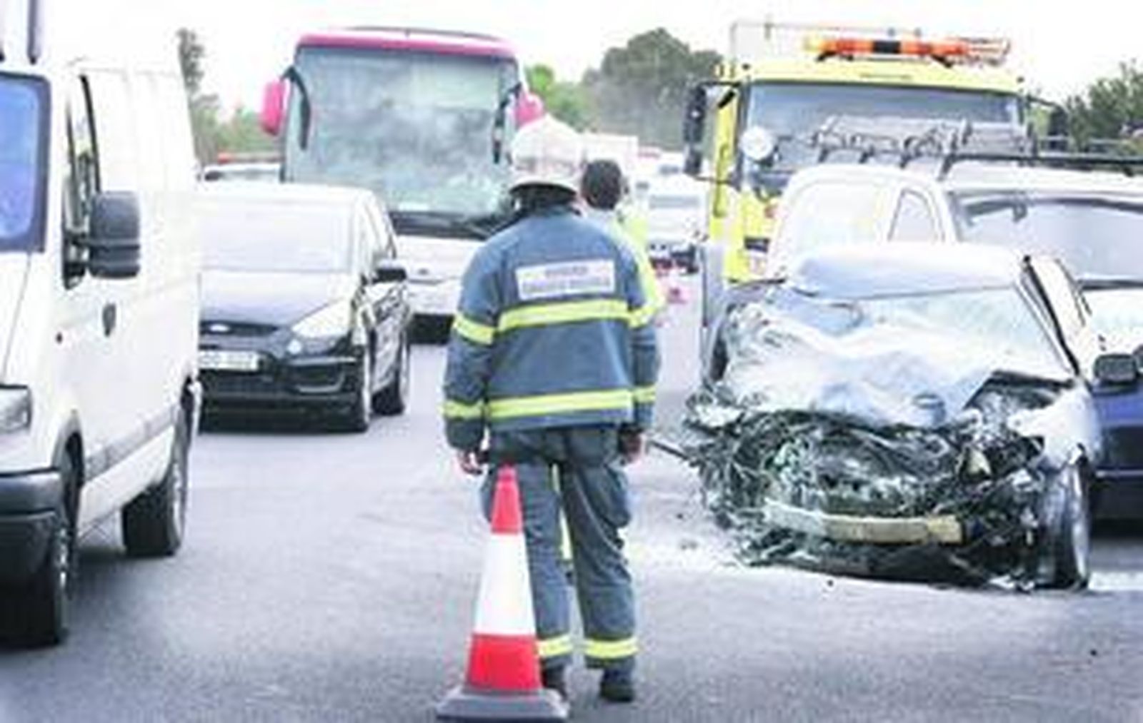 Retenciones de tráfico tras el accidente, con uno de los coches implicados a un lado de la calzada.