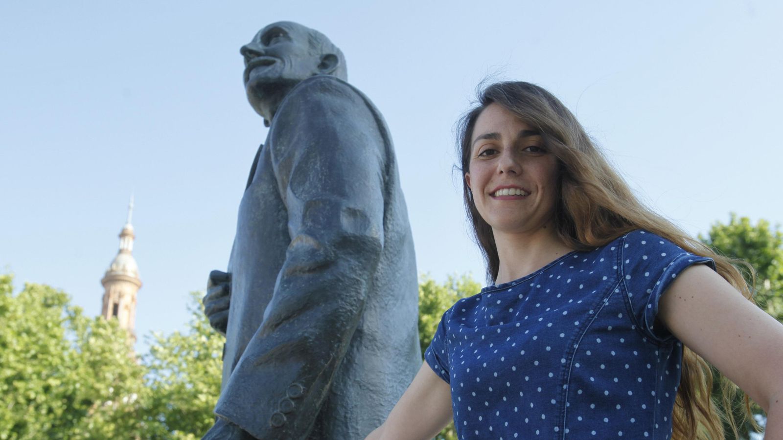 La ingeniera Noelia Chaves Méndez, autora de la tesis, posa junto a la estatua de Aníbal González que se encuentra frente a la Plaza de España.