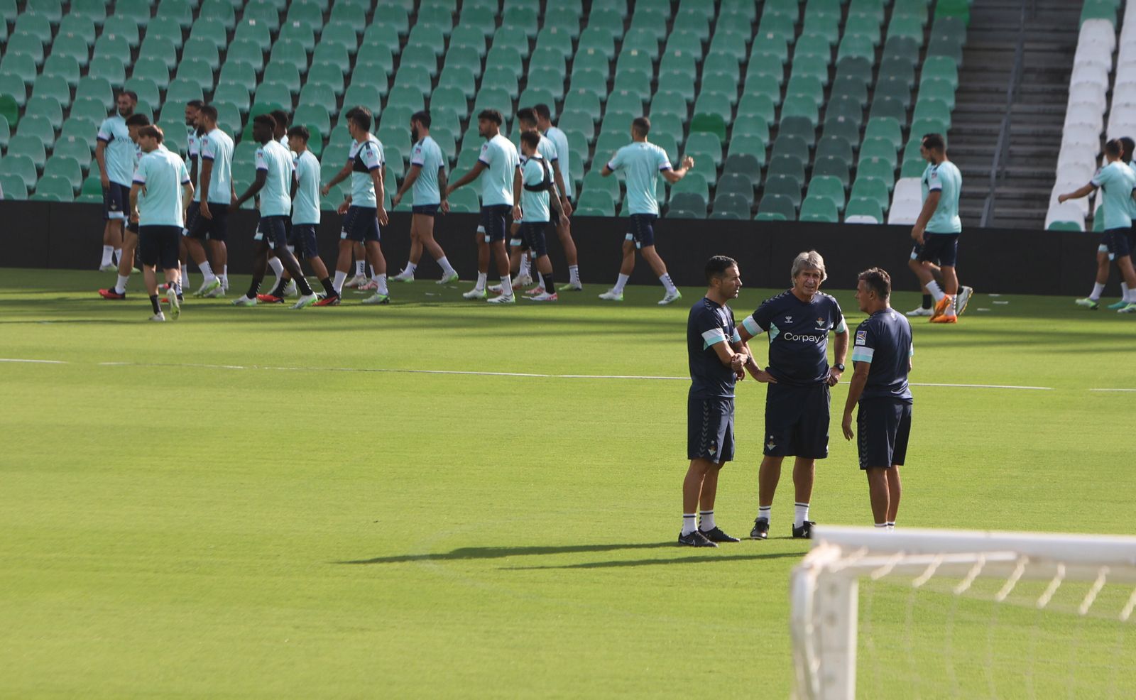 Manuel Pellegrini dialoga con Alexis y Fernando mientras sus jugadores hacen carrera continua para iniciar el calentamiento del entrenamiento.