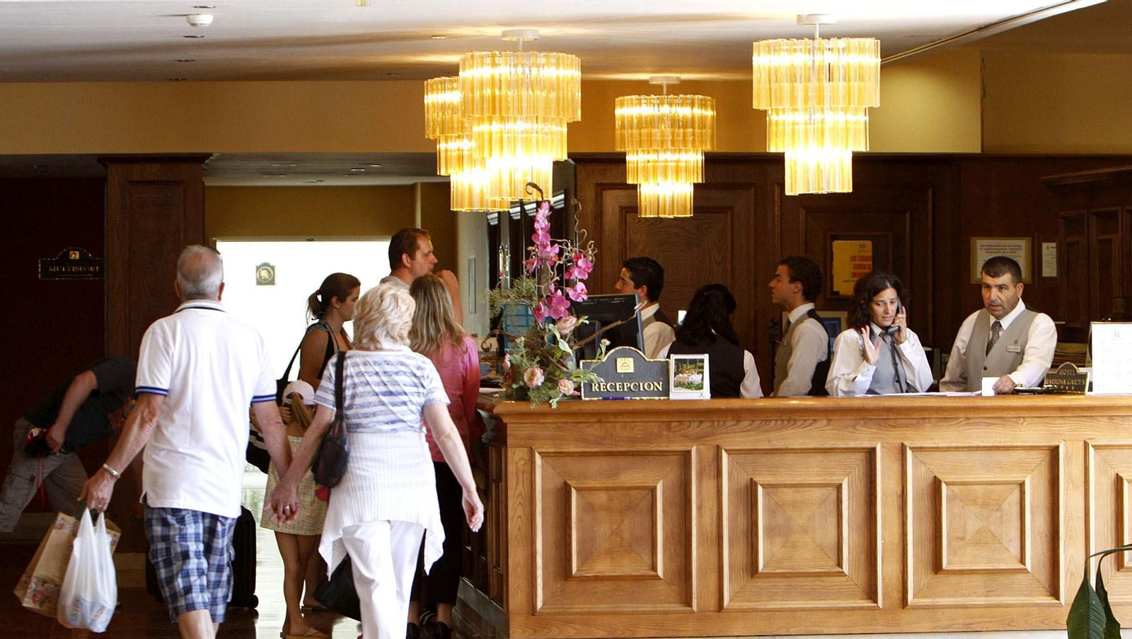 Varios turistas y empleados de un hotel andaluz en la recepción.