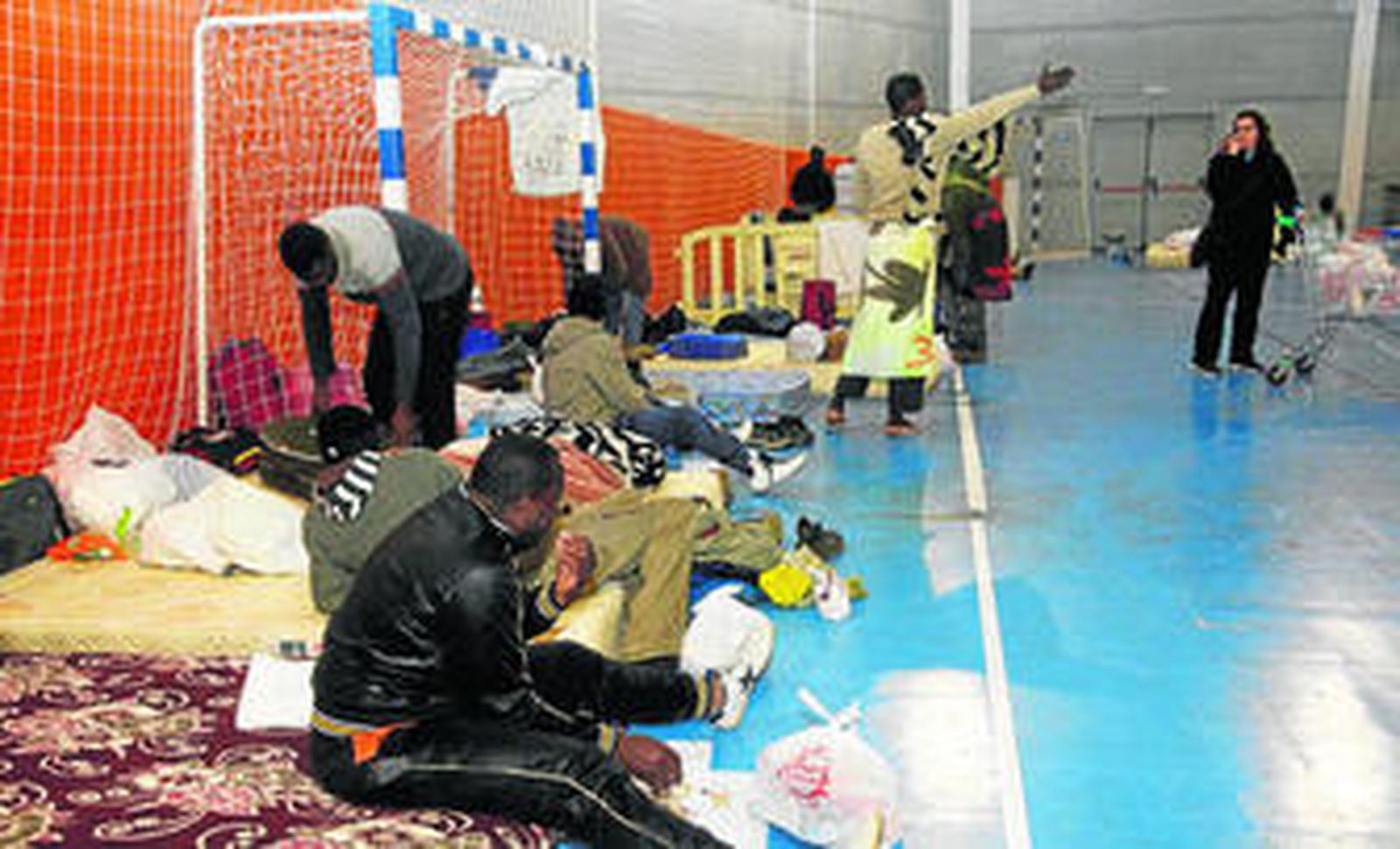 Los inmigrantes llegaban ayer tarde al polideportivo municipal, acondicionado por el Ayuntamiento para su acogida tras el incendio de sus chabolas.