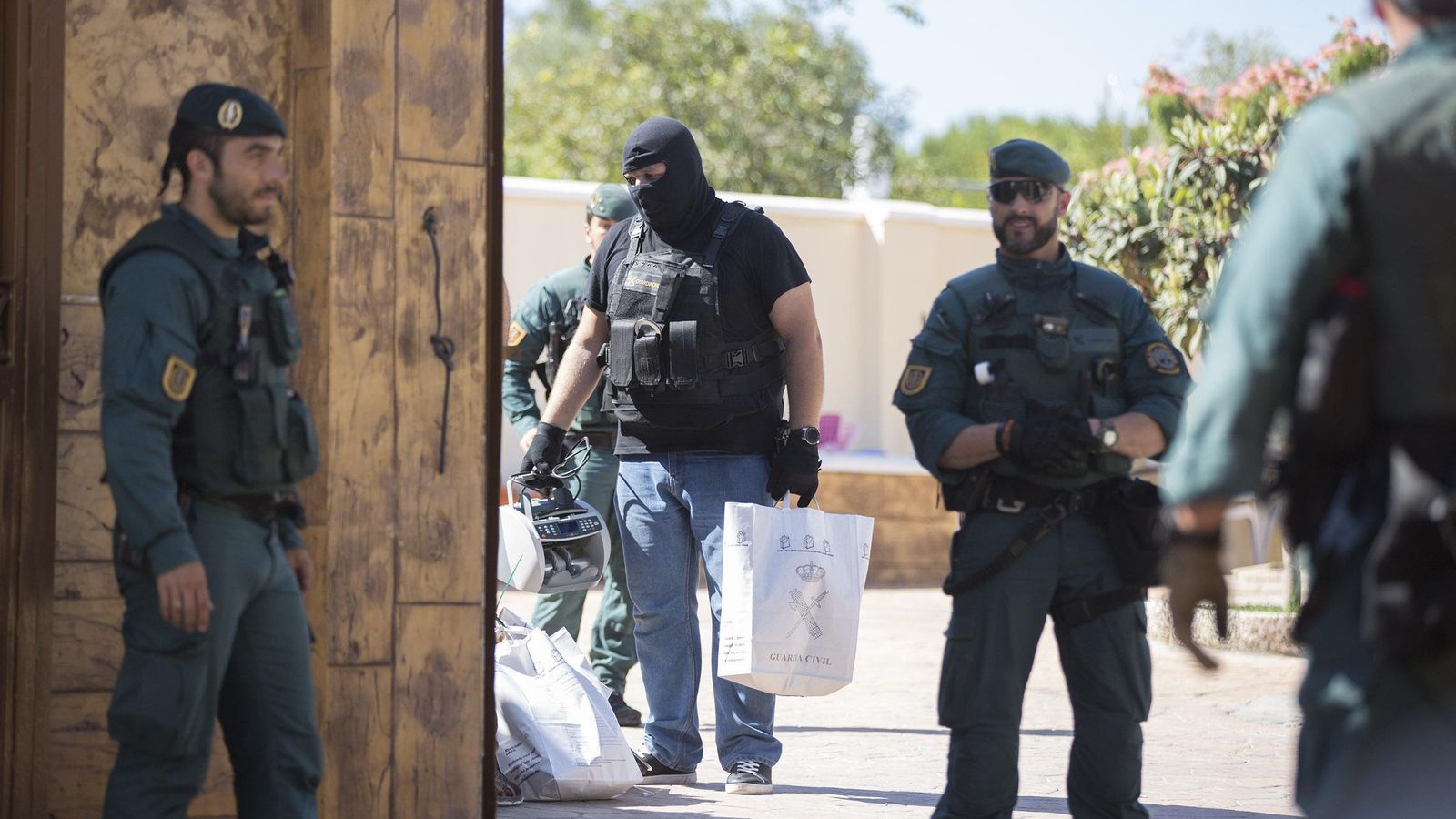 Un agente retira una máquina de contar billetes de la vivienda.