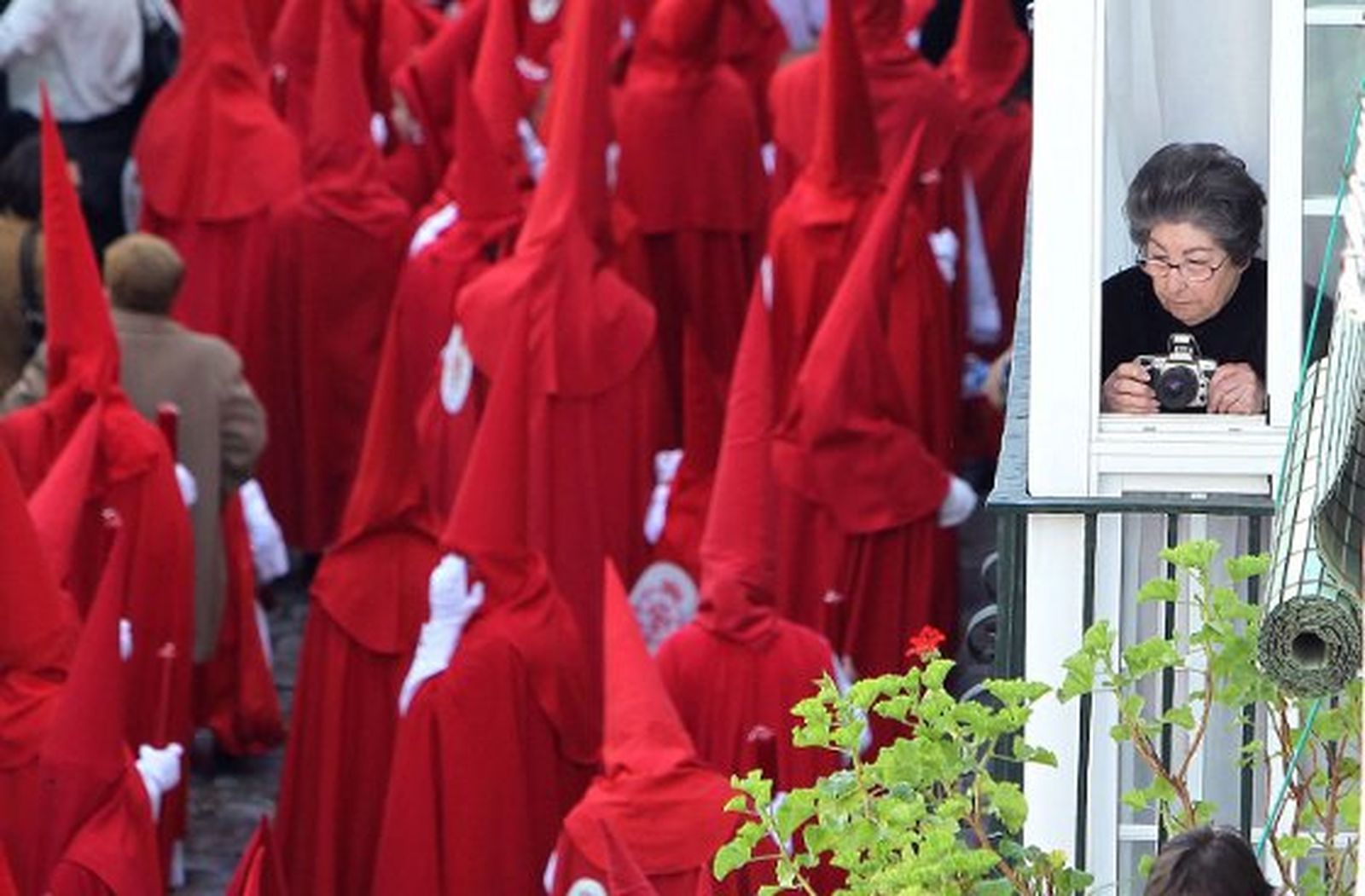 Una vecina de San Marcos ve pasar la cofradía de La Cena a la espera de captar una buena fotografía.

Foto: M.A. Gonzaléz