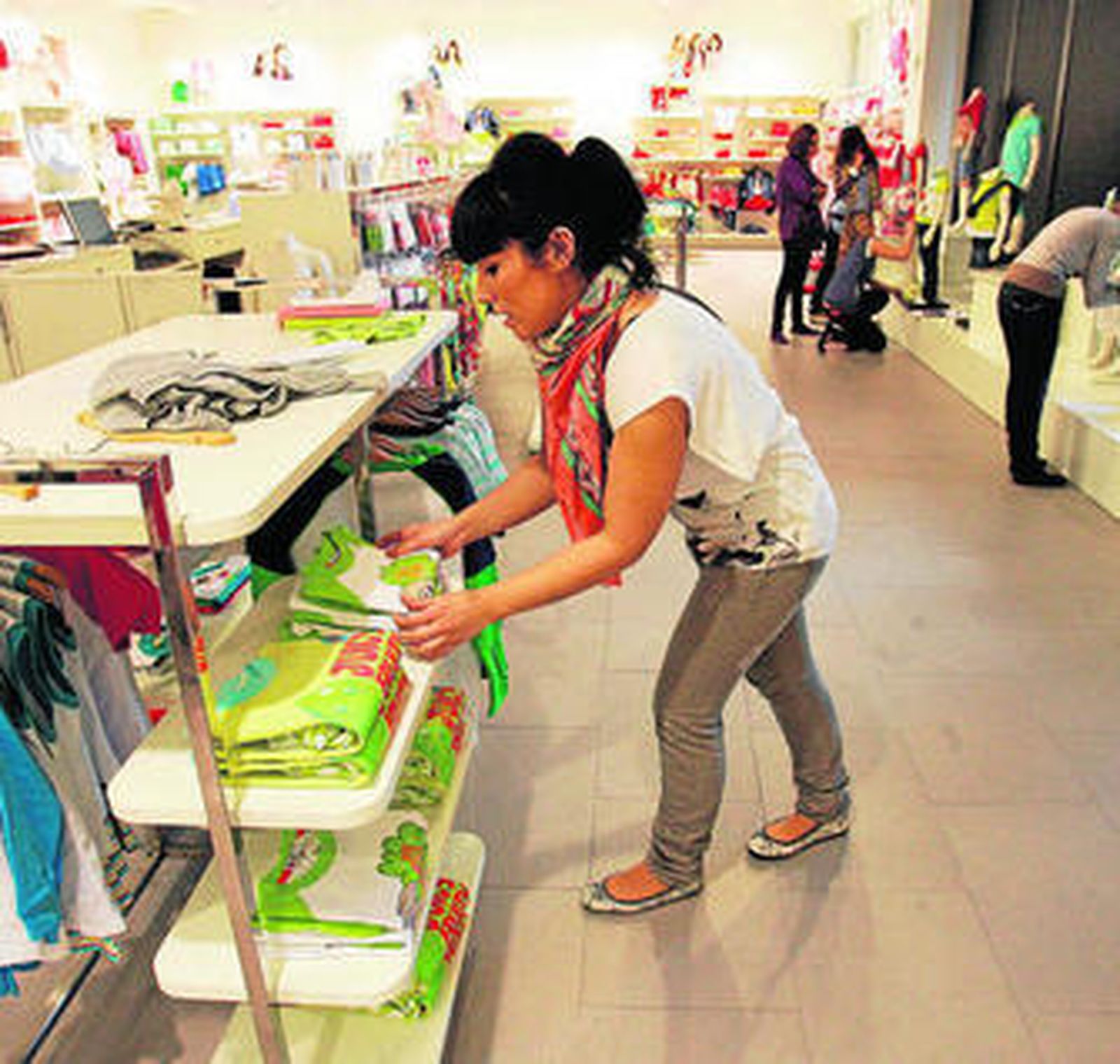 Una empleada coloca ropa en una estantería de una tienda de Charanga.