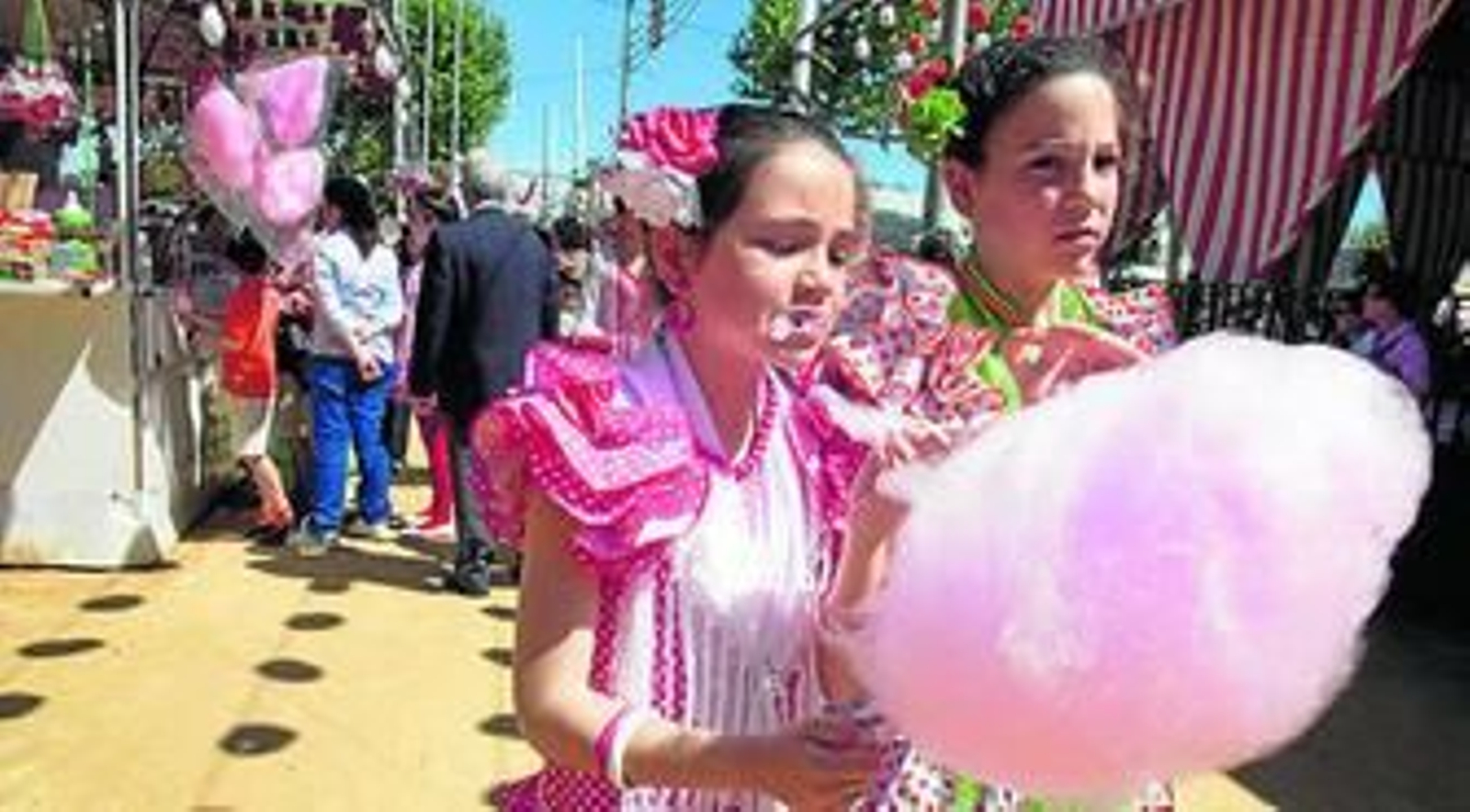 Dos niñas comen algodón dulce en el real de la Feria.