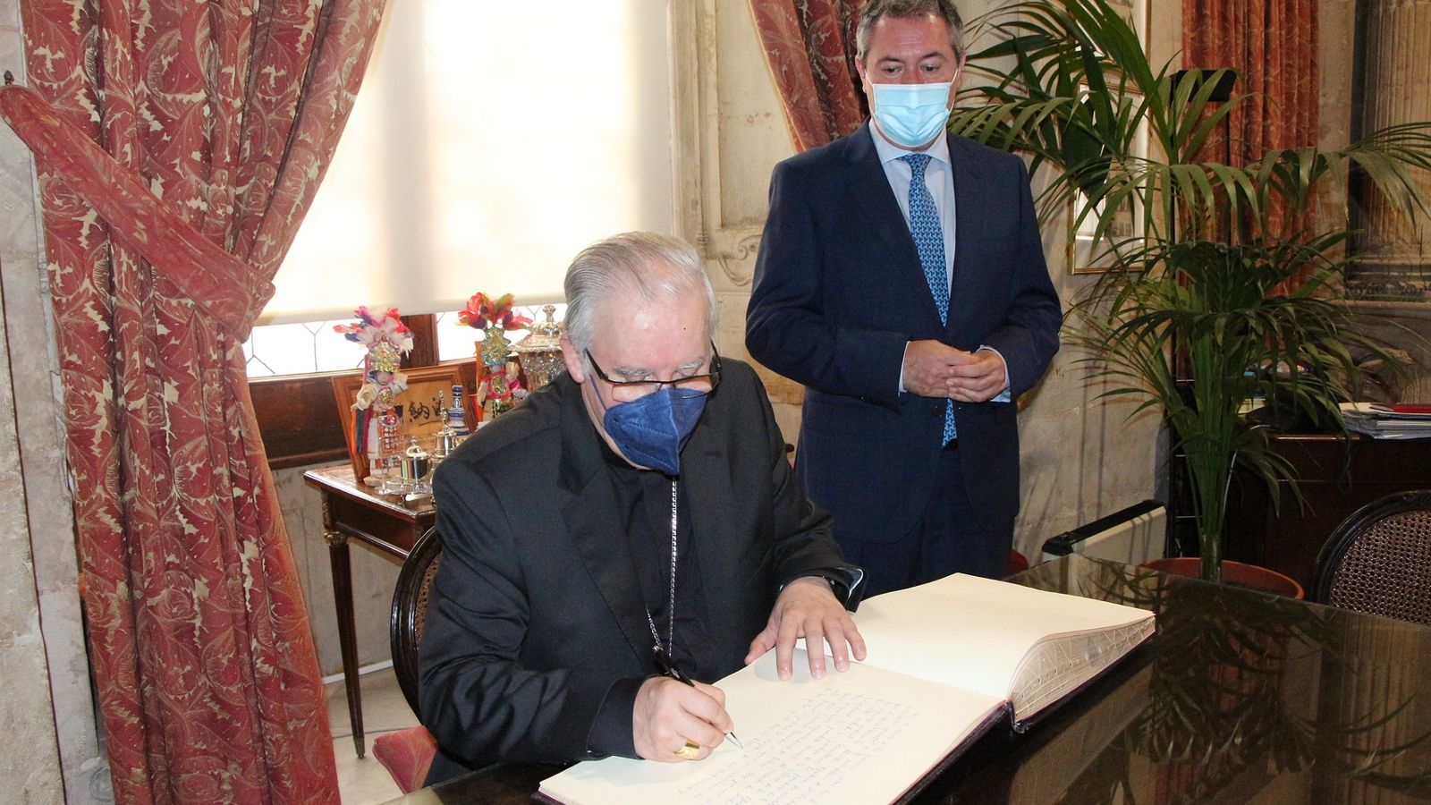 El arzobispo firma en el libro de honor del Ayuntamiento.