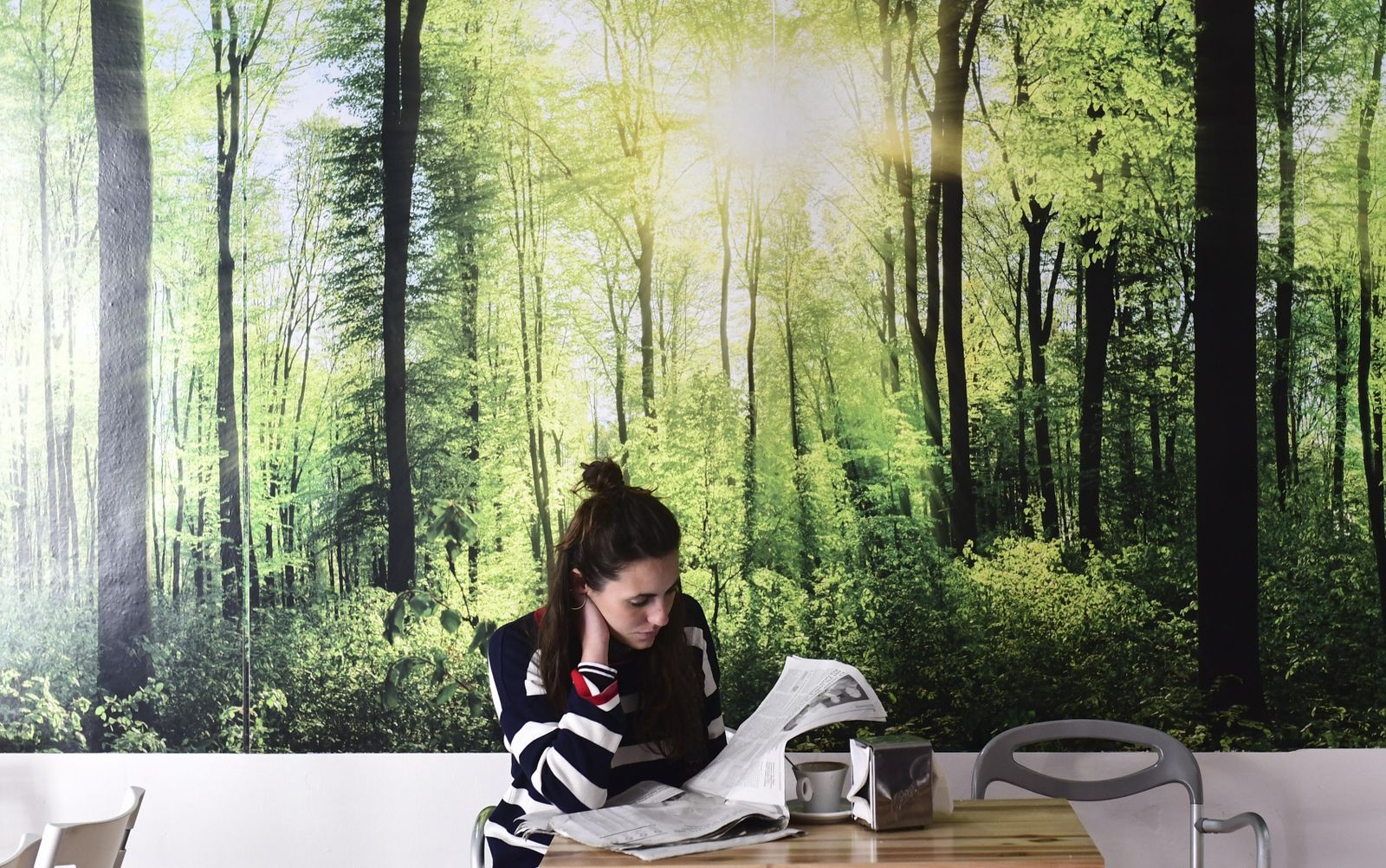 Una clienta lee el periódico mientras desayuna en el Café Pombo.