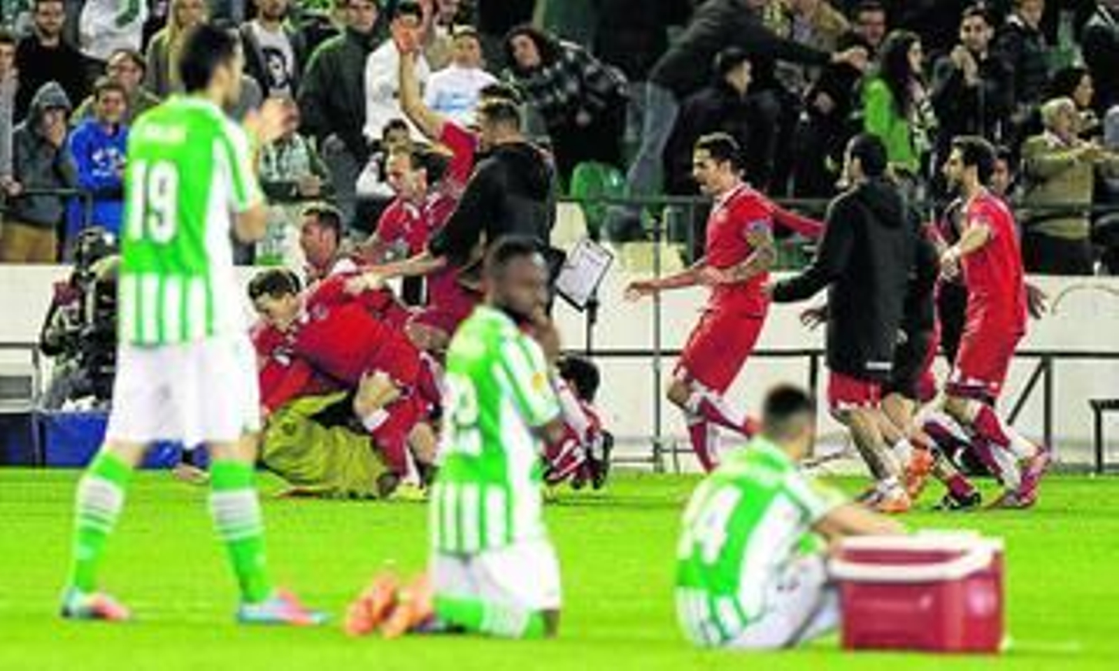 Los jugadores del Sevilla celebran la clasificación tras la tanda de penalti ante la impotencia de los béticos, eliminados.