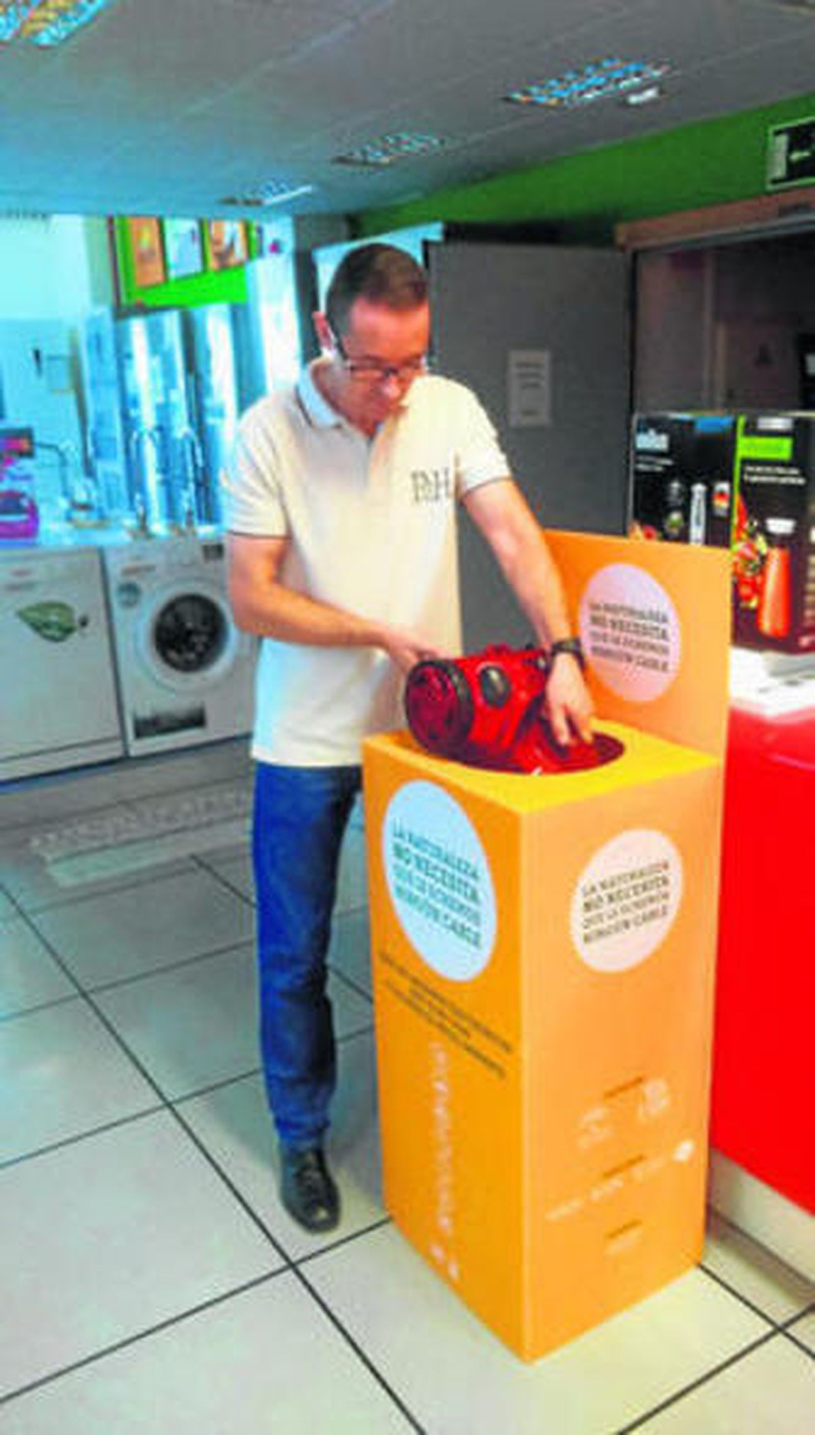 Un hombre deposita un electrodoméstico en un punto de reciclaje.