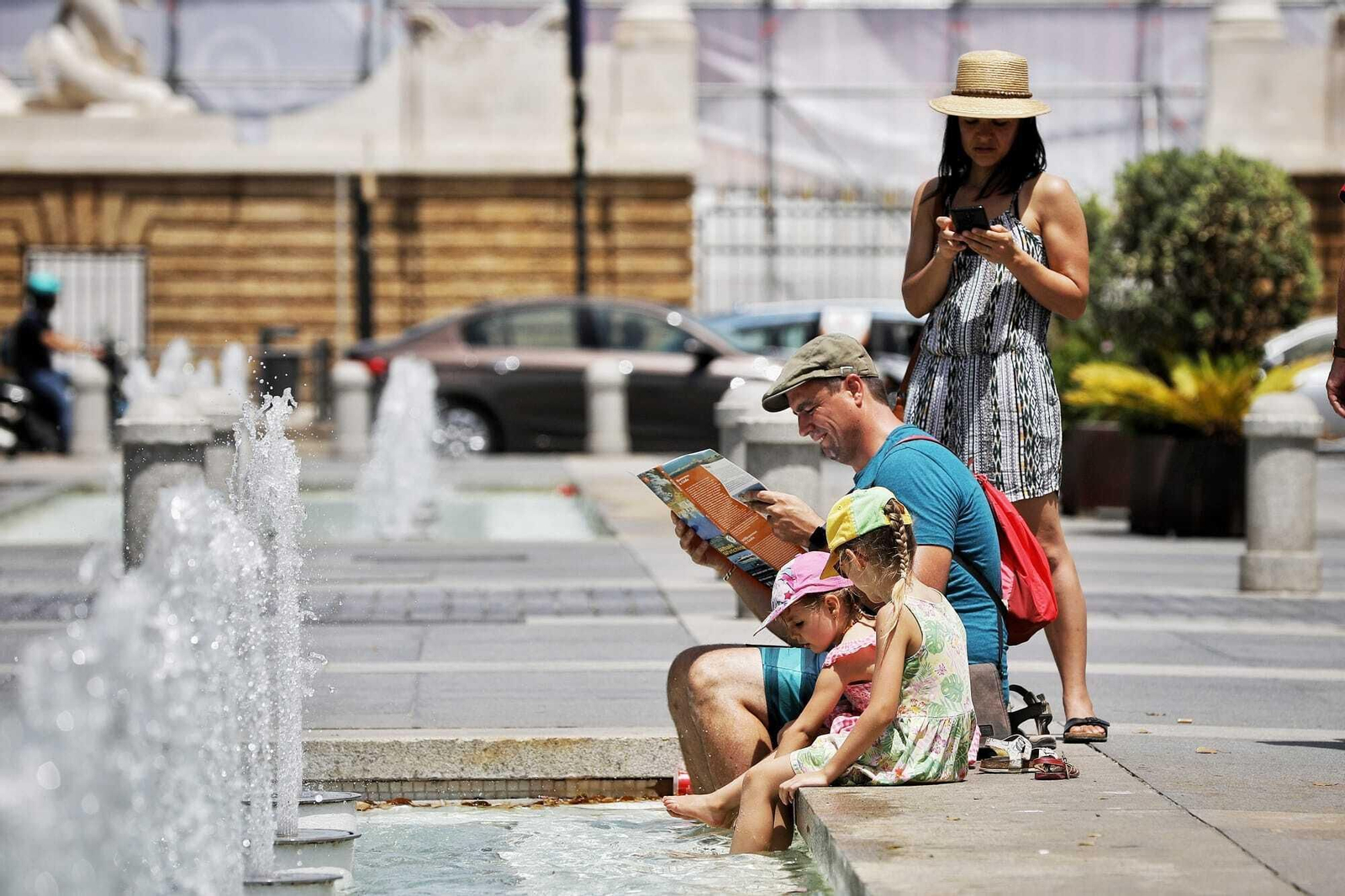 Unos turistas se refrescan en la plaza de San Juan de Dios en Cádiz.