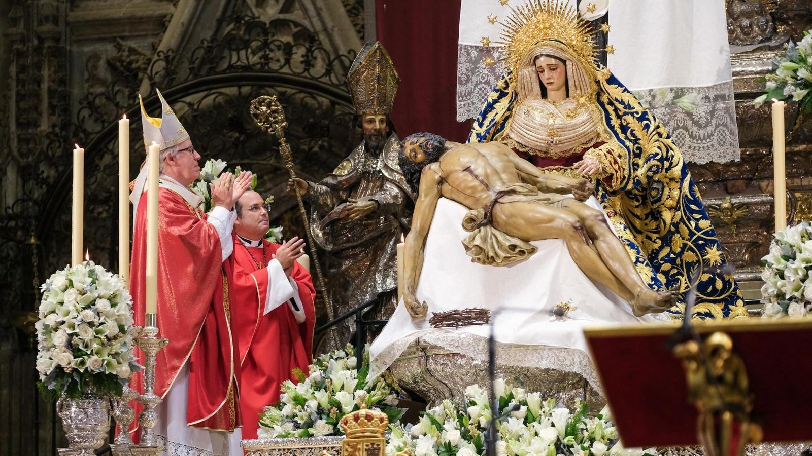 El arzobispo, aplaudiendo, justo después de colocarle la diadema a la Piedad