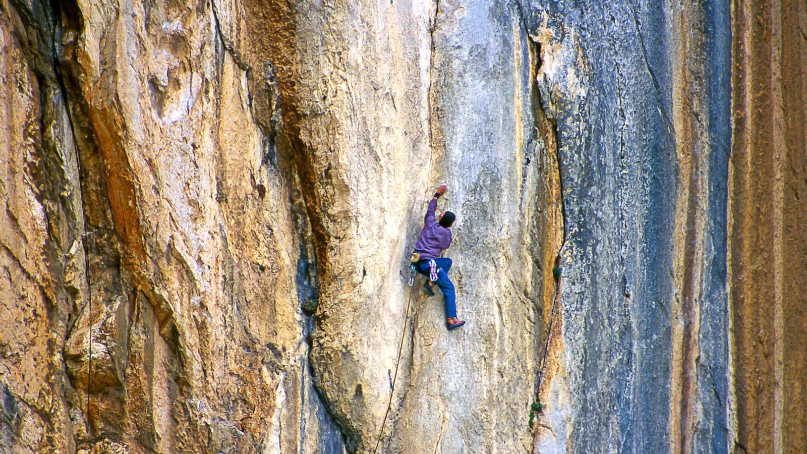 Una persona escala una de las paredes más verticales de El Chorro.