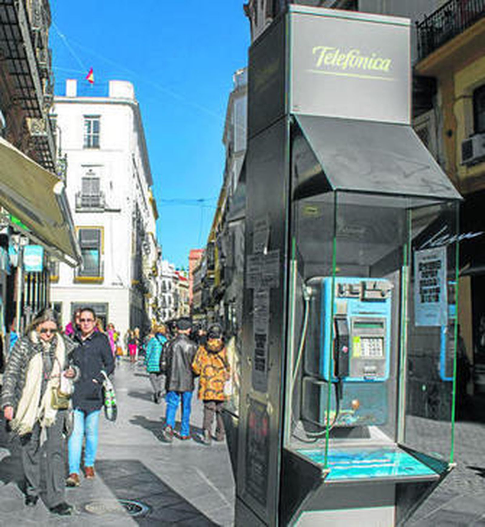 Ciudadanos transitando junto al teléfono público de la calle Tetuán.