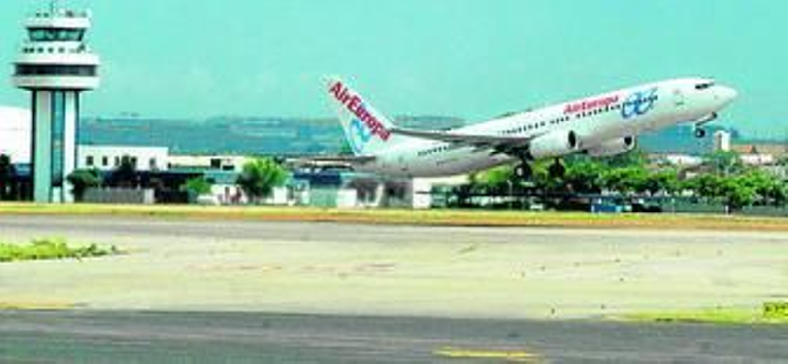 Un avión en las pistas del aeródromo de San Pablo de Sevilla, con la torre de control al fondo.