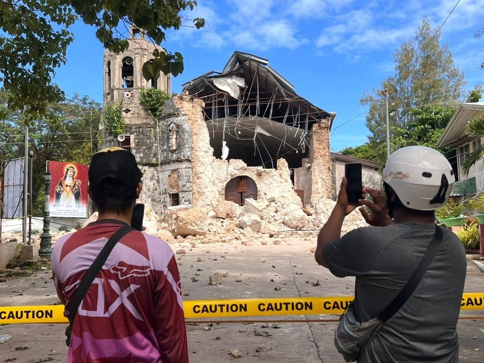 Dos personas tomas fotos de una iglesia destruida en la ciudad de Bogo.