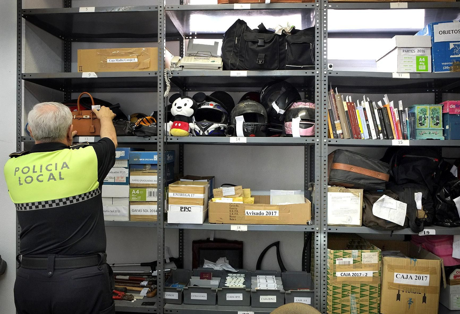 Un agente coloca un bolso en una de las estanterías.