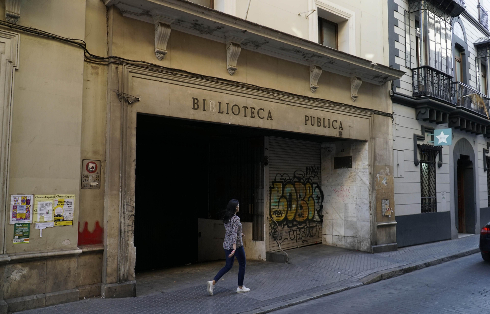Una mujer pasa por la entrada principal de la antigua Biblioteca municipal de la calle Alfonso XII.