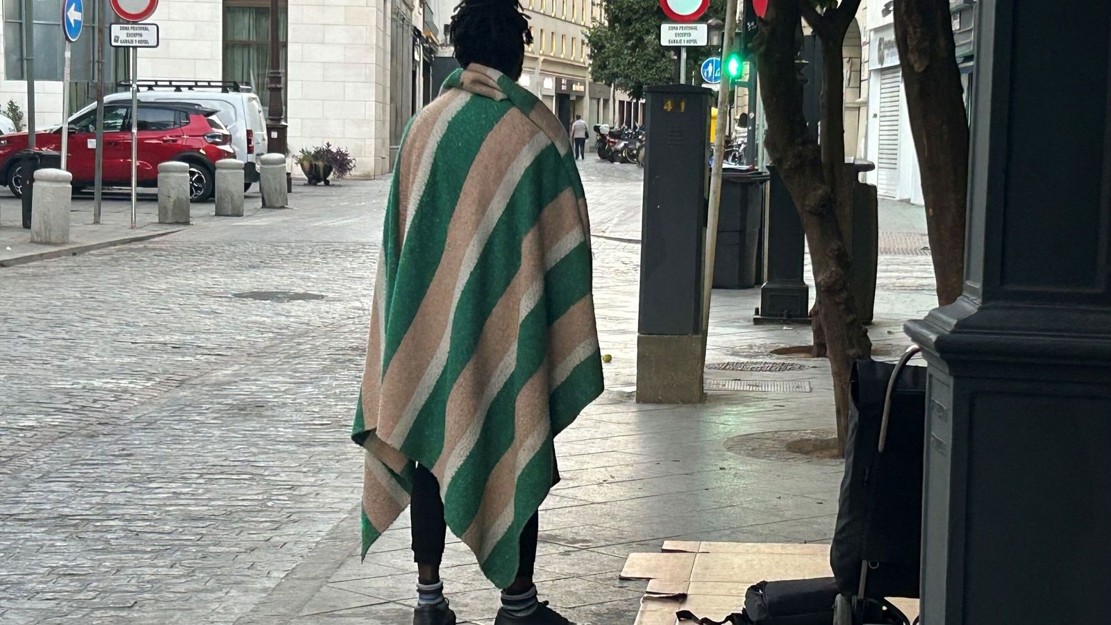 Una persona sin hogar se cubre del frío con la manta en el centro de la ciudad.