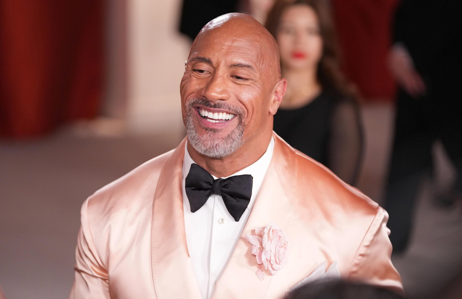Dwayne Johnson embutido en un esmoquin color salmón, demasiado apretado el hombre de acción