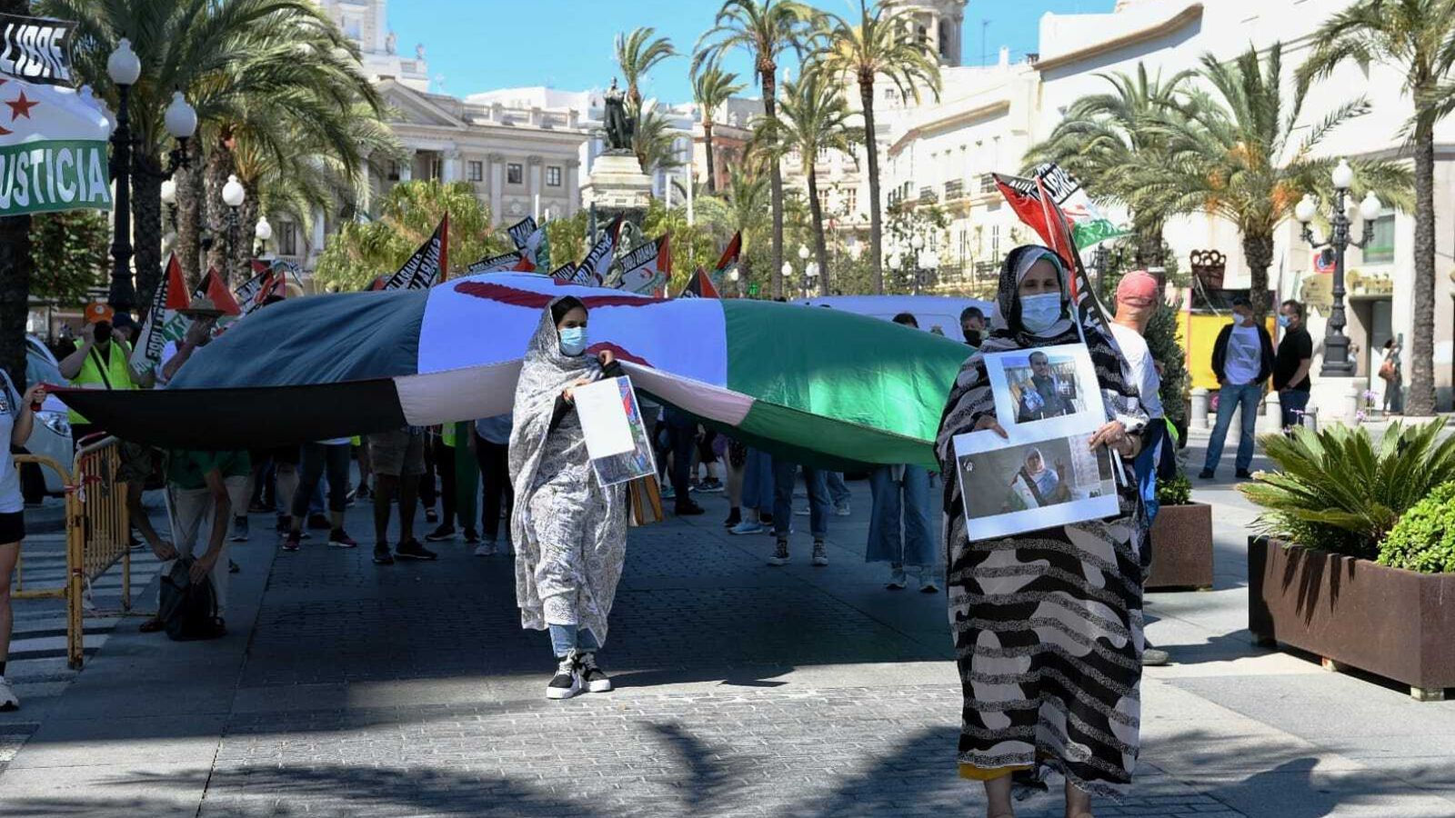 Dos mujeres saharauis con fotos de presos y de agresiones, en la cabecera de la manifestación.