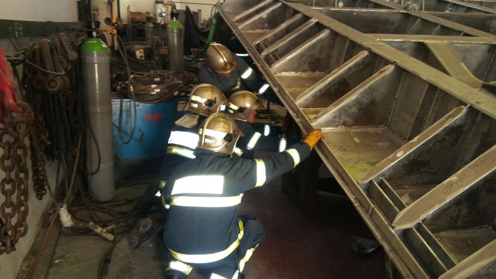 Los bomberos inspeccionan la plancha que aplastó a los dos trabajadores.