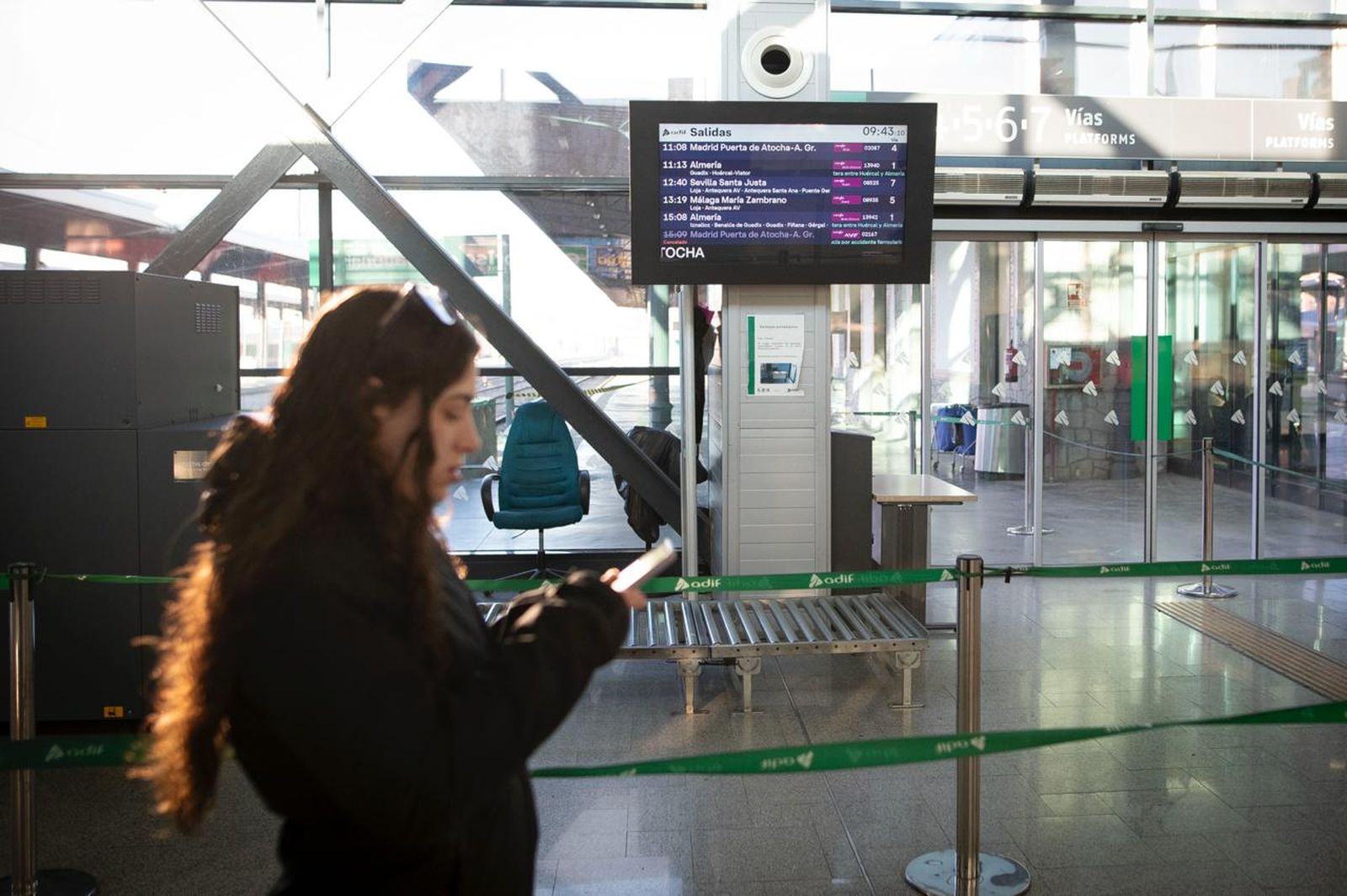 Una pasajera consulta su movil frente a las pantallas de salidas de los trenes de la estación