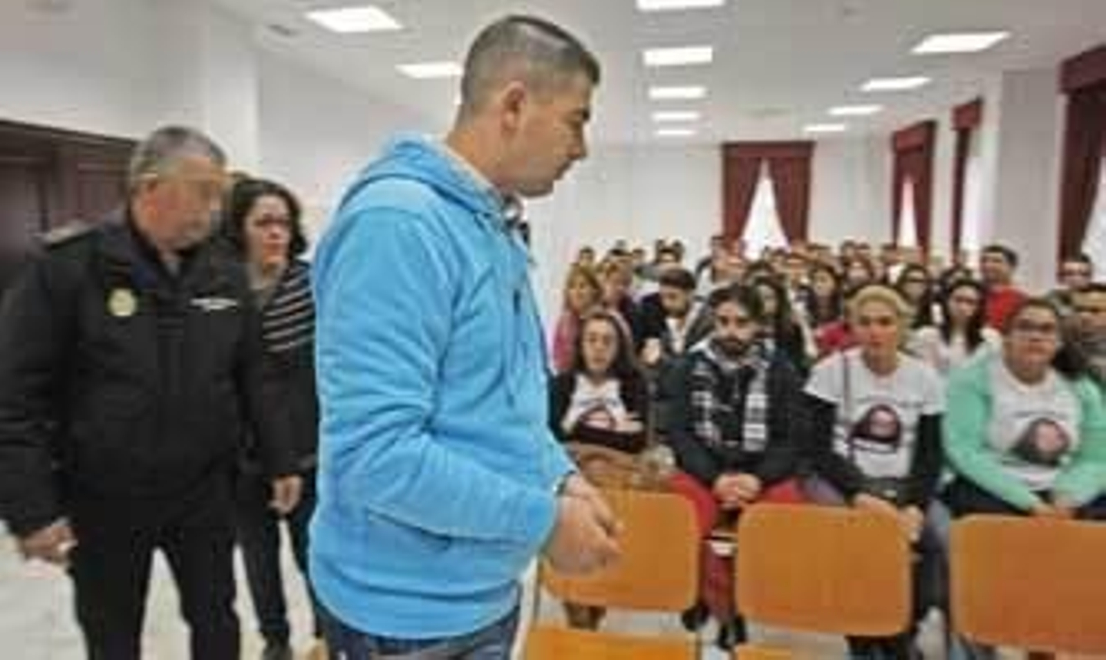 El acusado accede al banquillo, finalmente se sentó junto a su abogado, mientras amigos de la víctima portan su imagen en unas camisetas. /Pascual