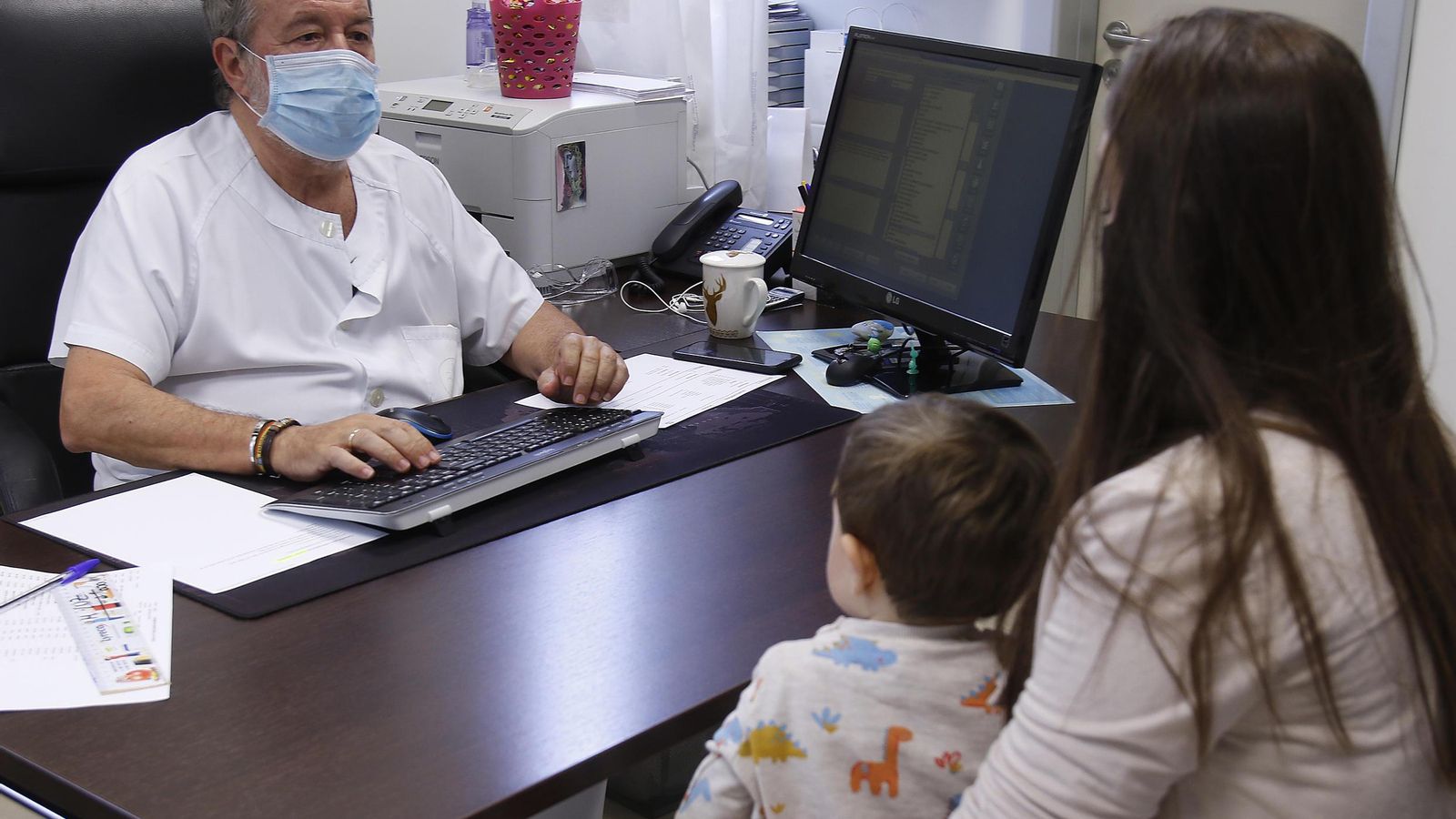 El veterano pediatra atiende a una madre y a su hijo.