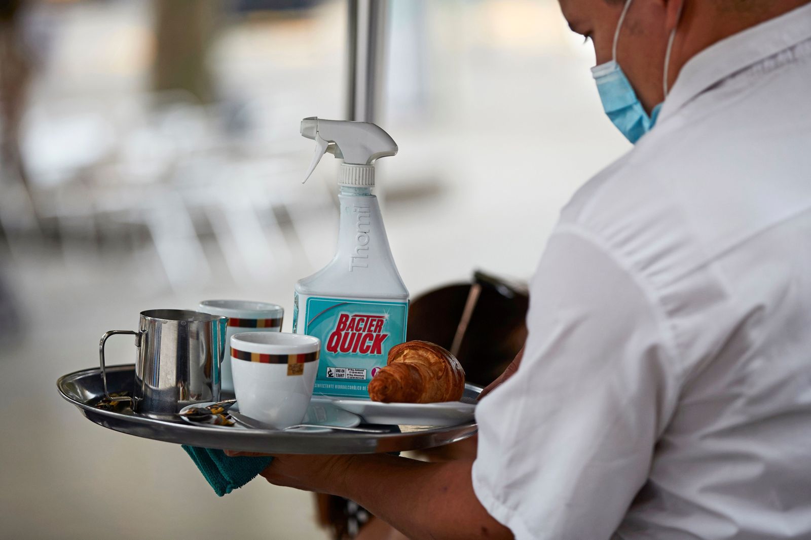 Un camarero atiende una mesa protegido con una mascarillas.