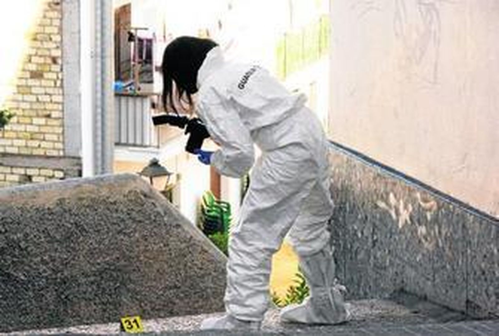Una agente de la Policía Científica de la Guardia Civil recabando pruebas en el callejón cercano a la casa de la familia Márquez por donde huyó el presunto parricida.