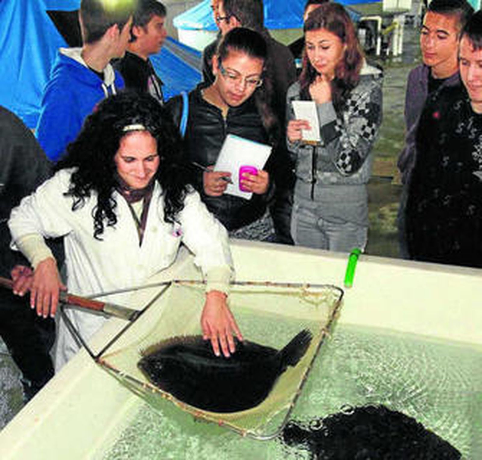 Unos estudiantes observan el trabajo de una operaria de Aguas del Pino.