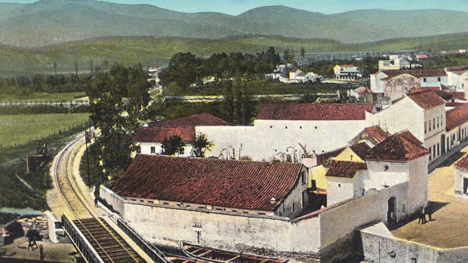 En primer término, el río de la Miel y la línea del ferrocarril con el puente de hierro. Detrás y a la derecha, la Capilla del Santo Cristo de la Alameda. La fotografía fue tomada hacia 1906.