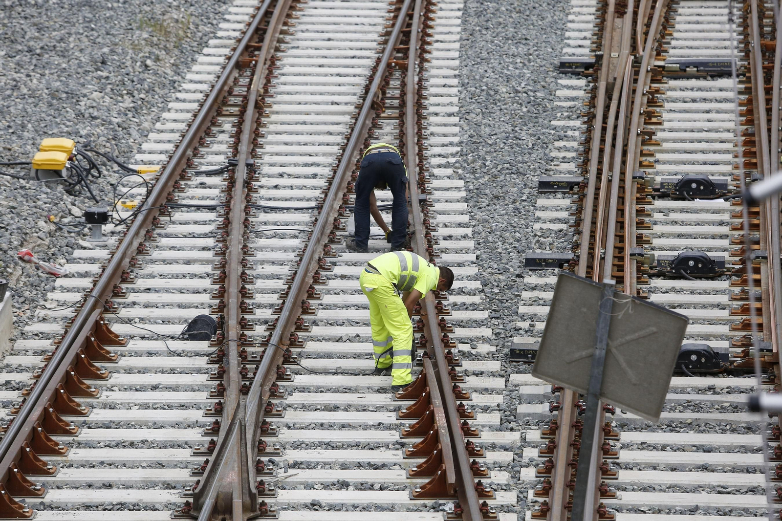Dos operarios trabajan entre raíles y traviesas de tren. Dos operarios trabajan entre raíles y traviesas de tren.
