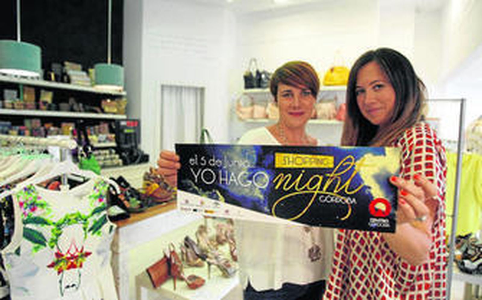 Dos mujeres posan con el cartel de la Shopping Night en uno de los establecimientos del centro.