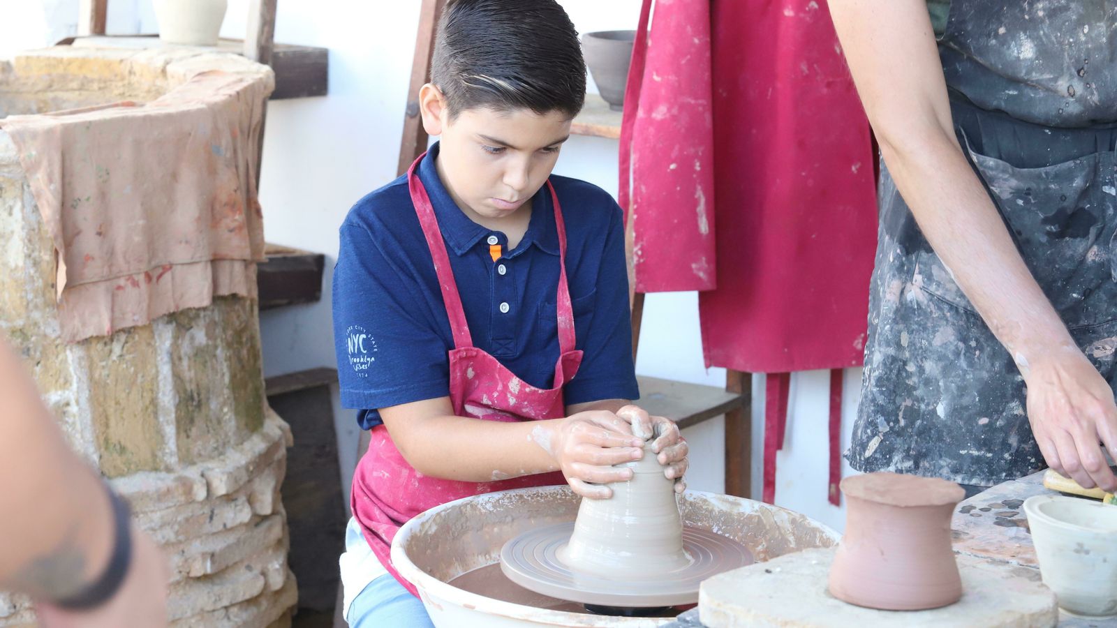 Un niño aprende los entresijos de la alfarería.