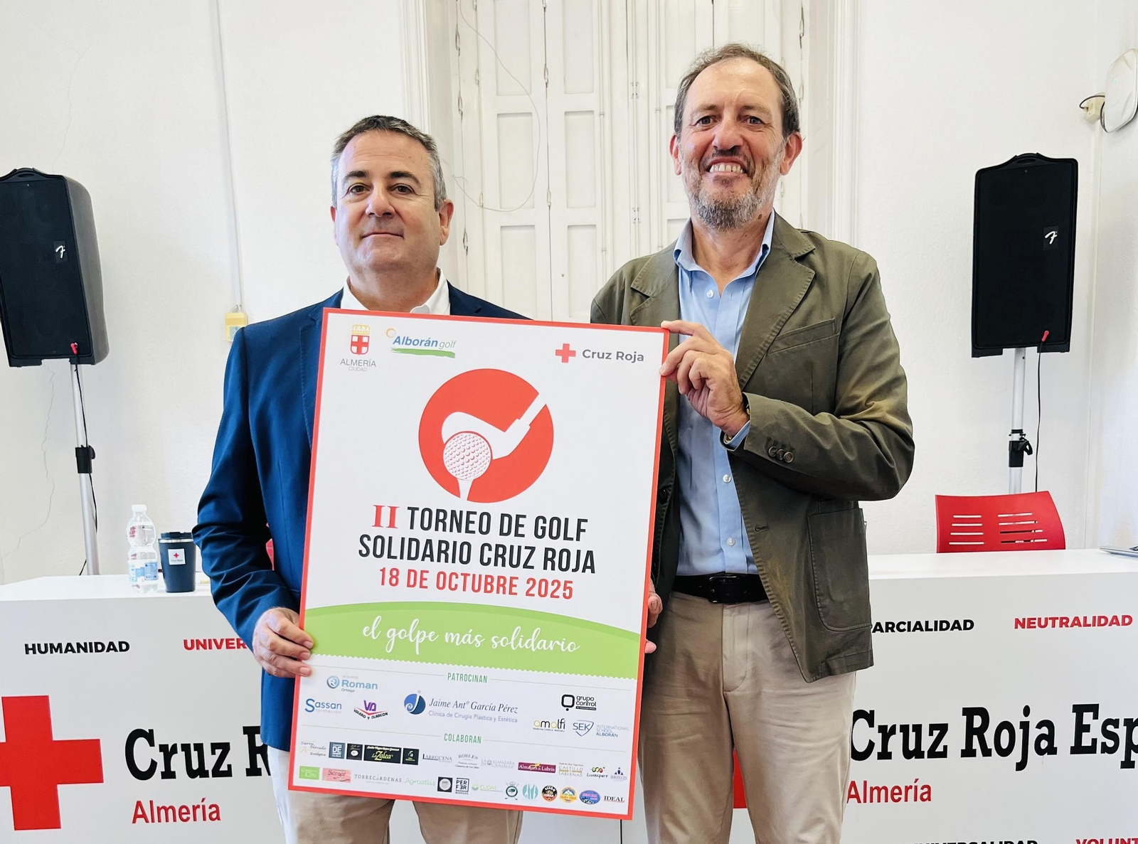 El presidente provincial de Cruz Roja en Almería y el director de Alborán Golf posan con el cartel del torneo.